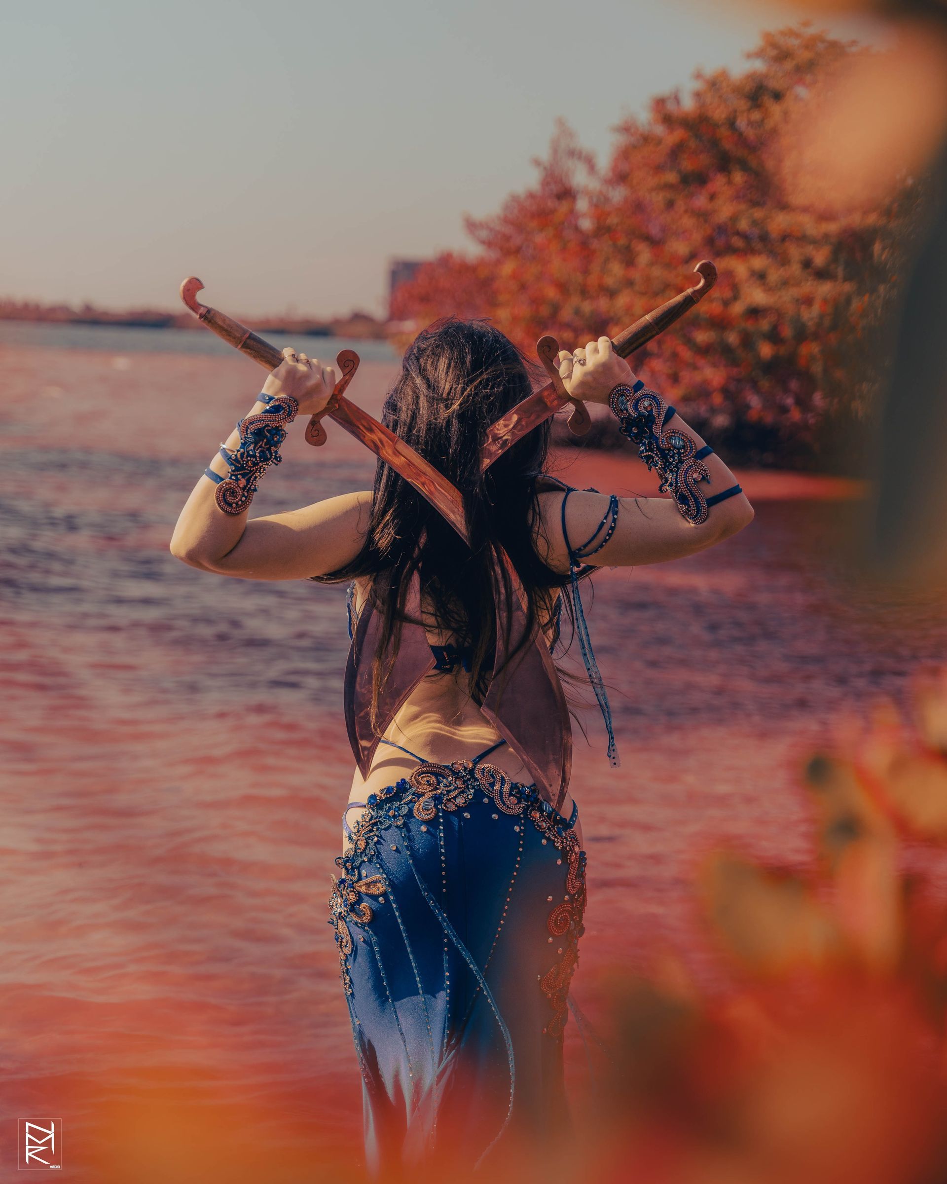 Bellydancer Azeeria standing in the water holding two swords.