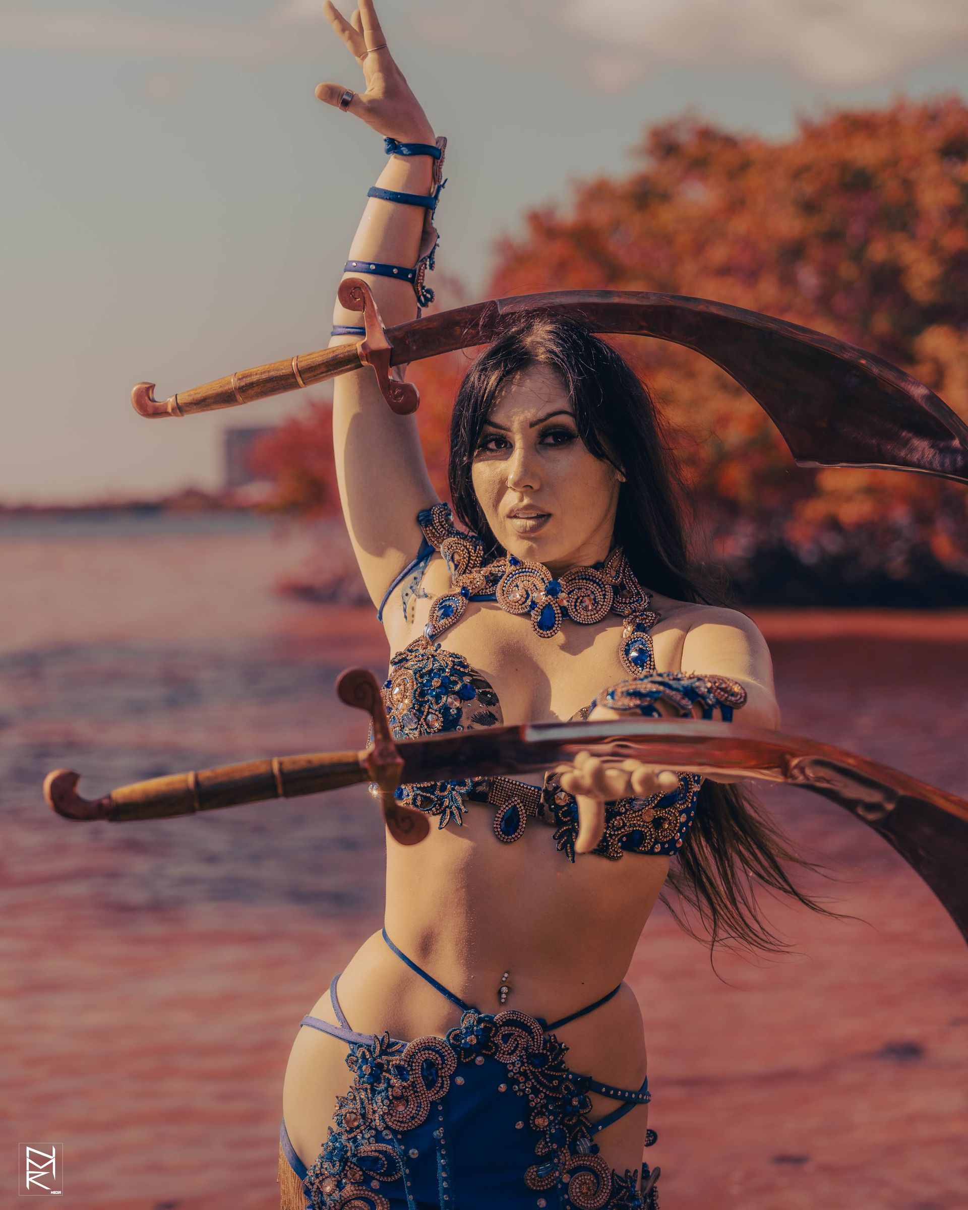 Azeeria Azizah in a belly dancer balancing two swords in her hands and head.
