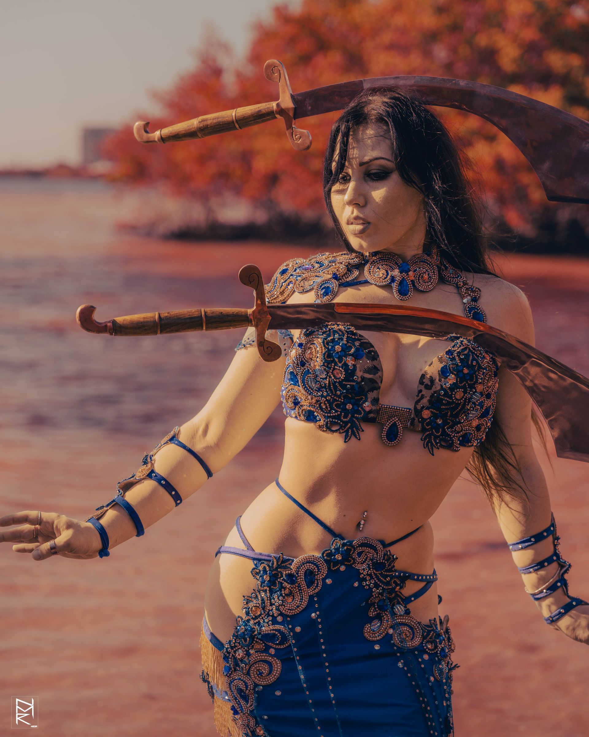 A photo of the Belly Dancer Azeeria Azizah balancing 2 swords on her head and body in the water at cypress beach, Tampa Fl