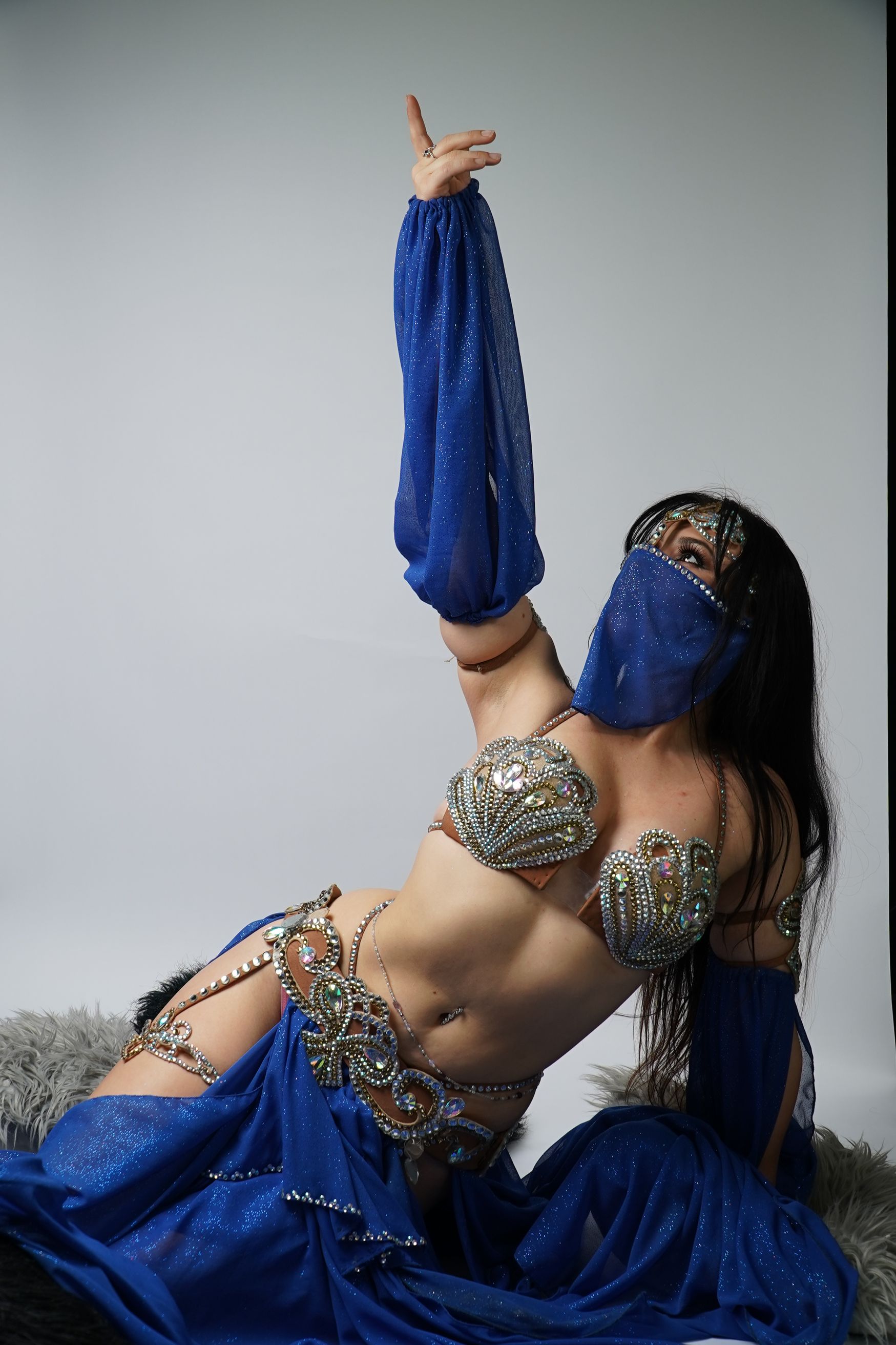 Belly dancer Azeeria Azizah is wearing a blue and silver outfit with a blue veil. 