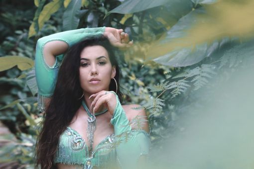 Belly dancer Azeeria Azizah in a green dress is standing in the jungle in Puerto Rico. 