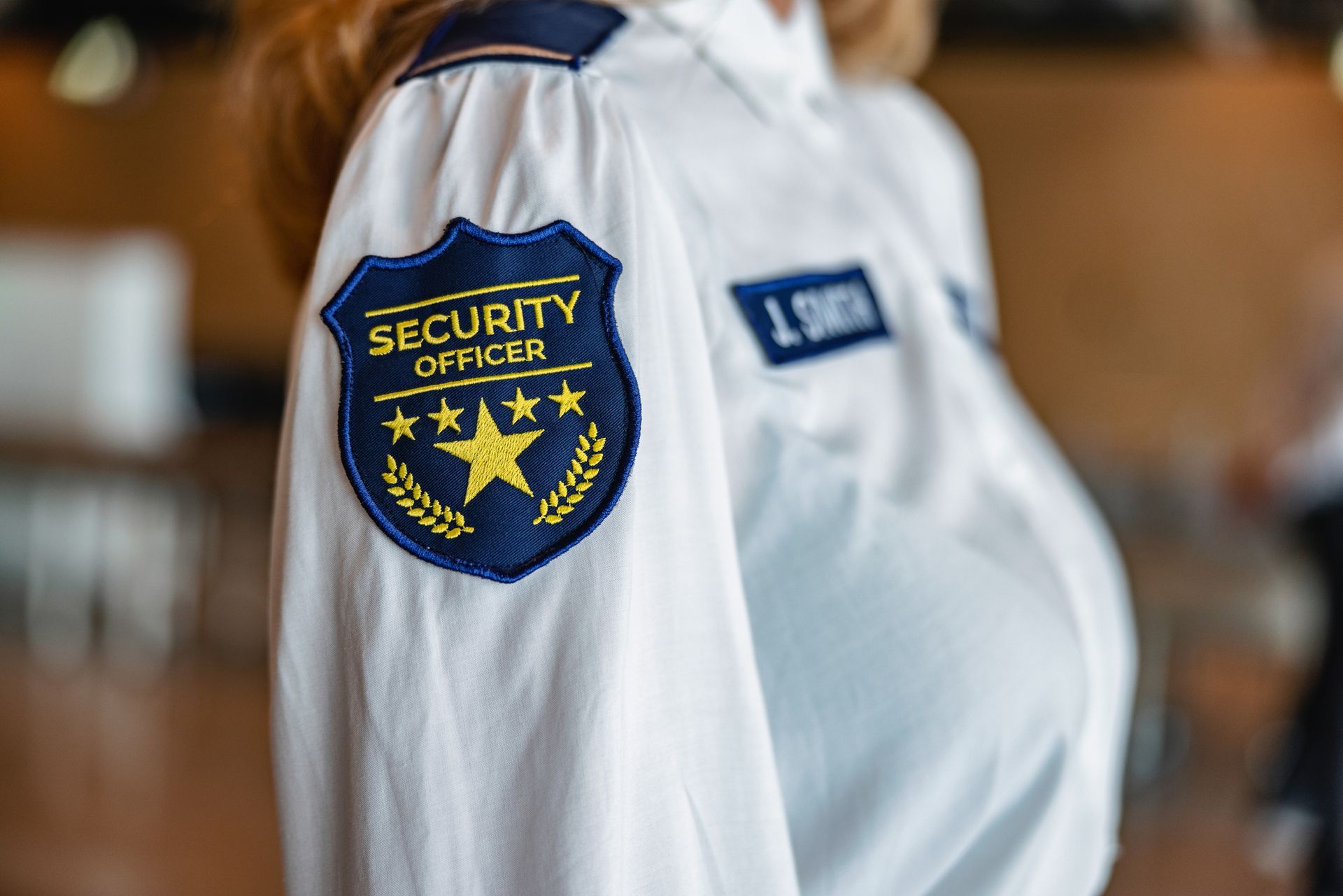 A female security worker wearing a uniform shirt with a name tag.