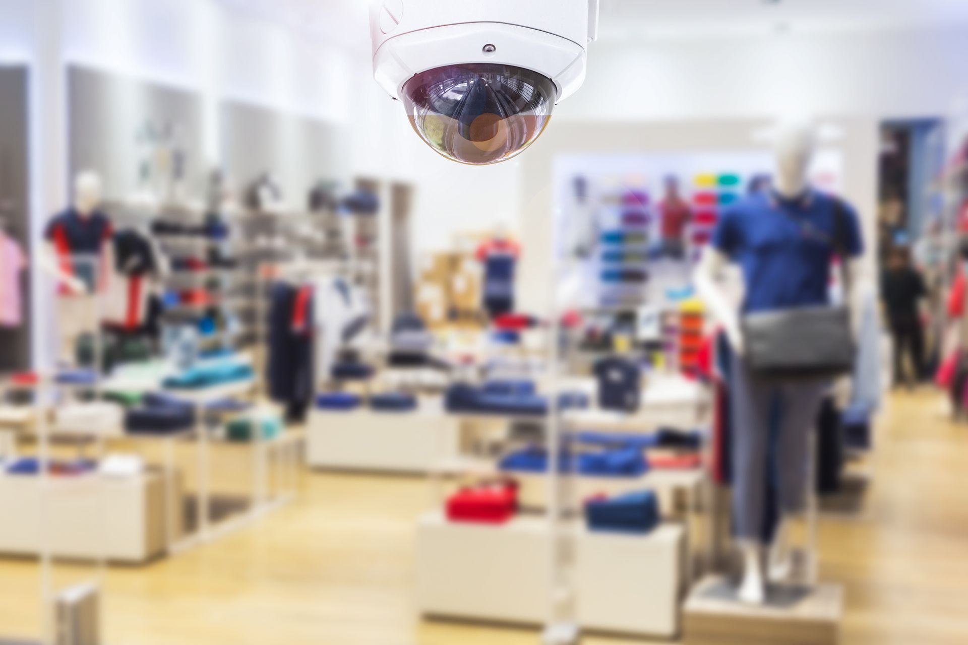 Security camera in clothing store, focused on merchandise, mannequins, and blurred interior.