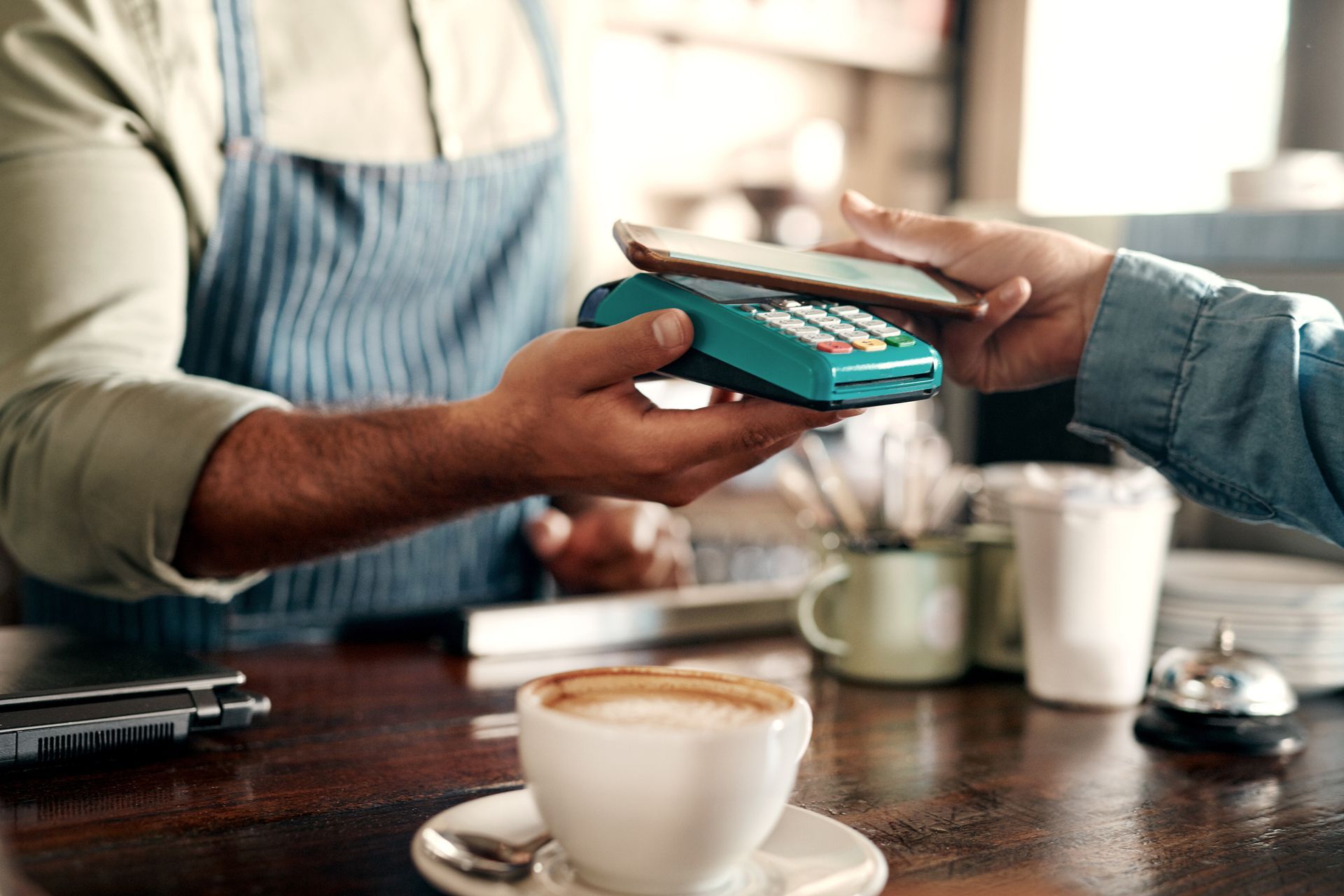 A person is paying for a cup of coffee with a cell phone.