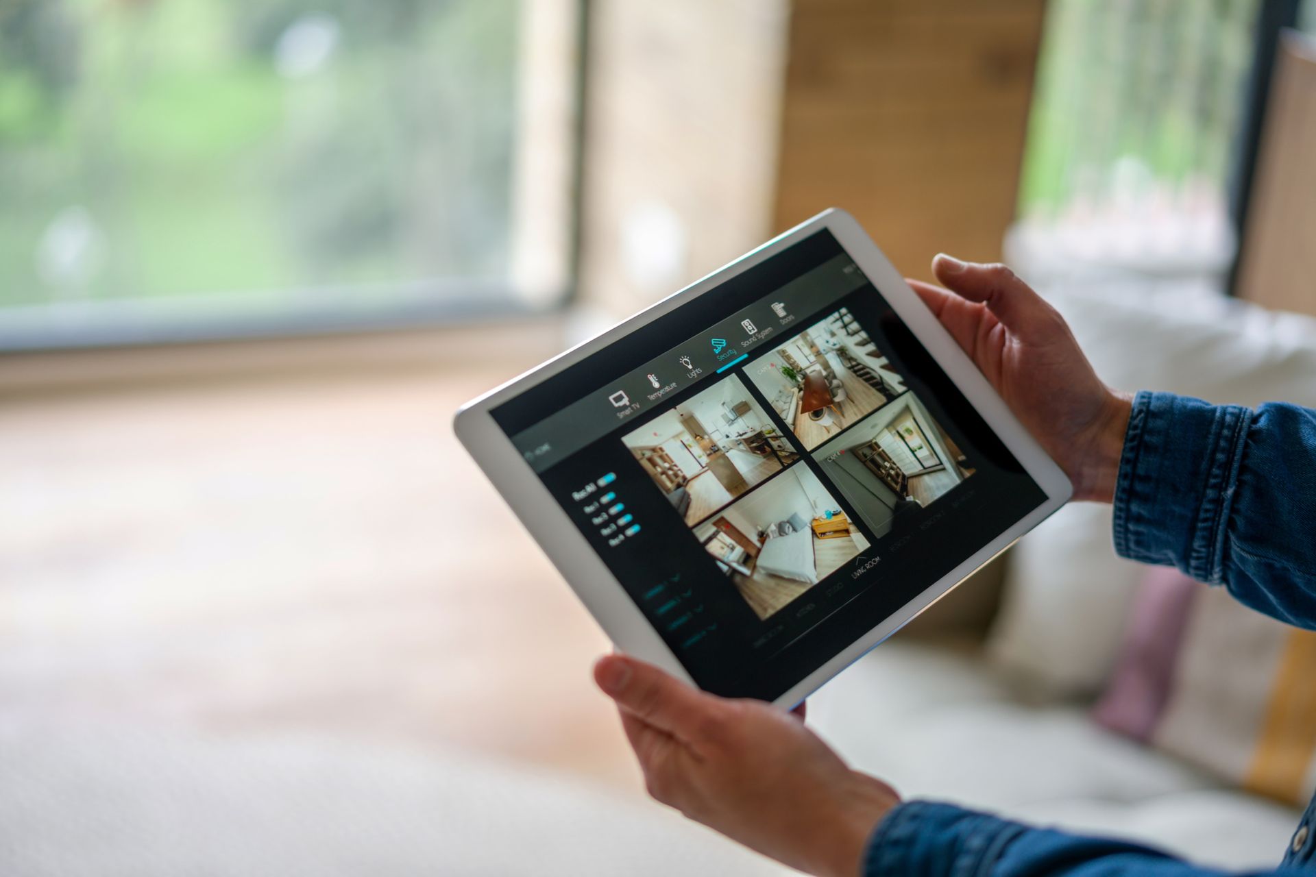 Close-up of a woman monitoring all the rooms with a home security system using a tablet.