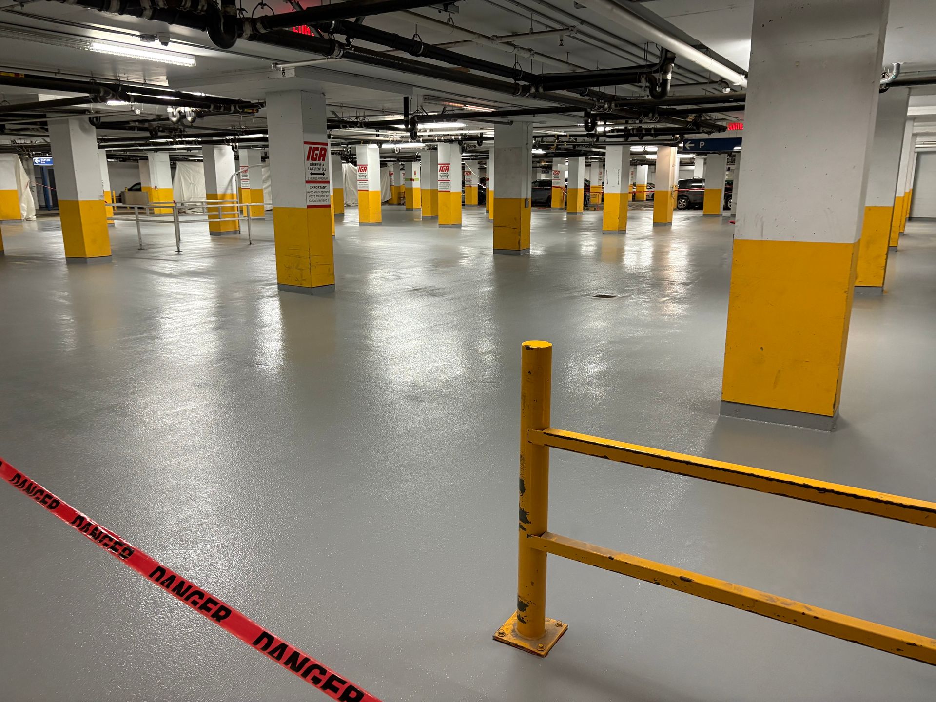 Un grand parking vide avec des piliers jaunes et une clôture jaune.
