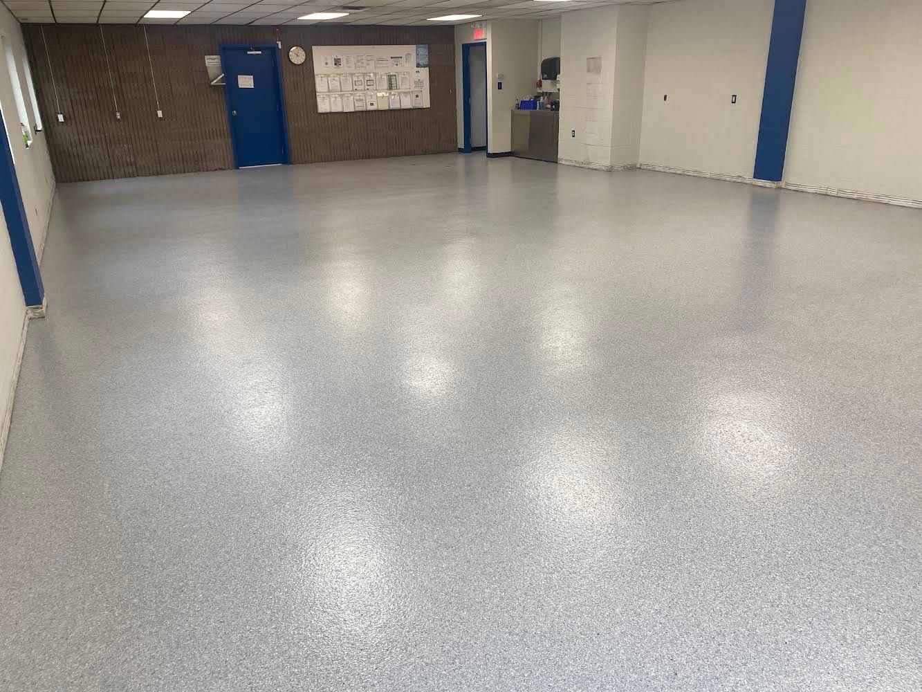 A large room with a white floor and a blue door