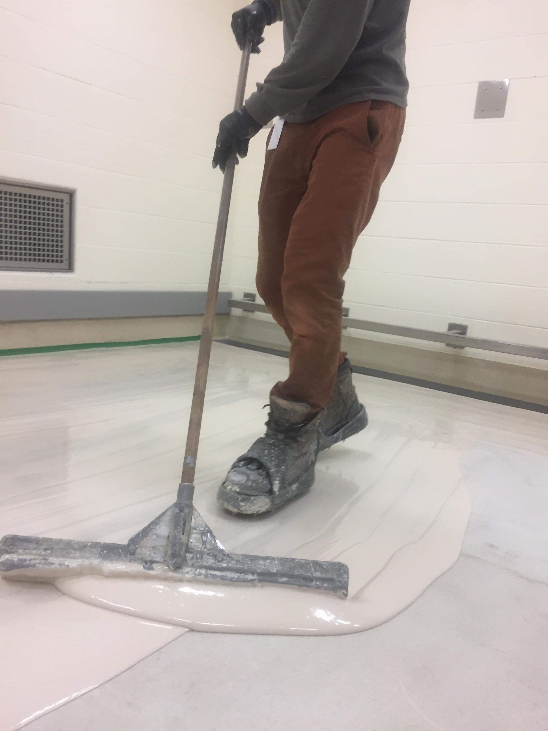 Une personne se tient debout sur une surface blanche tenant une serpillère