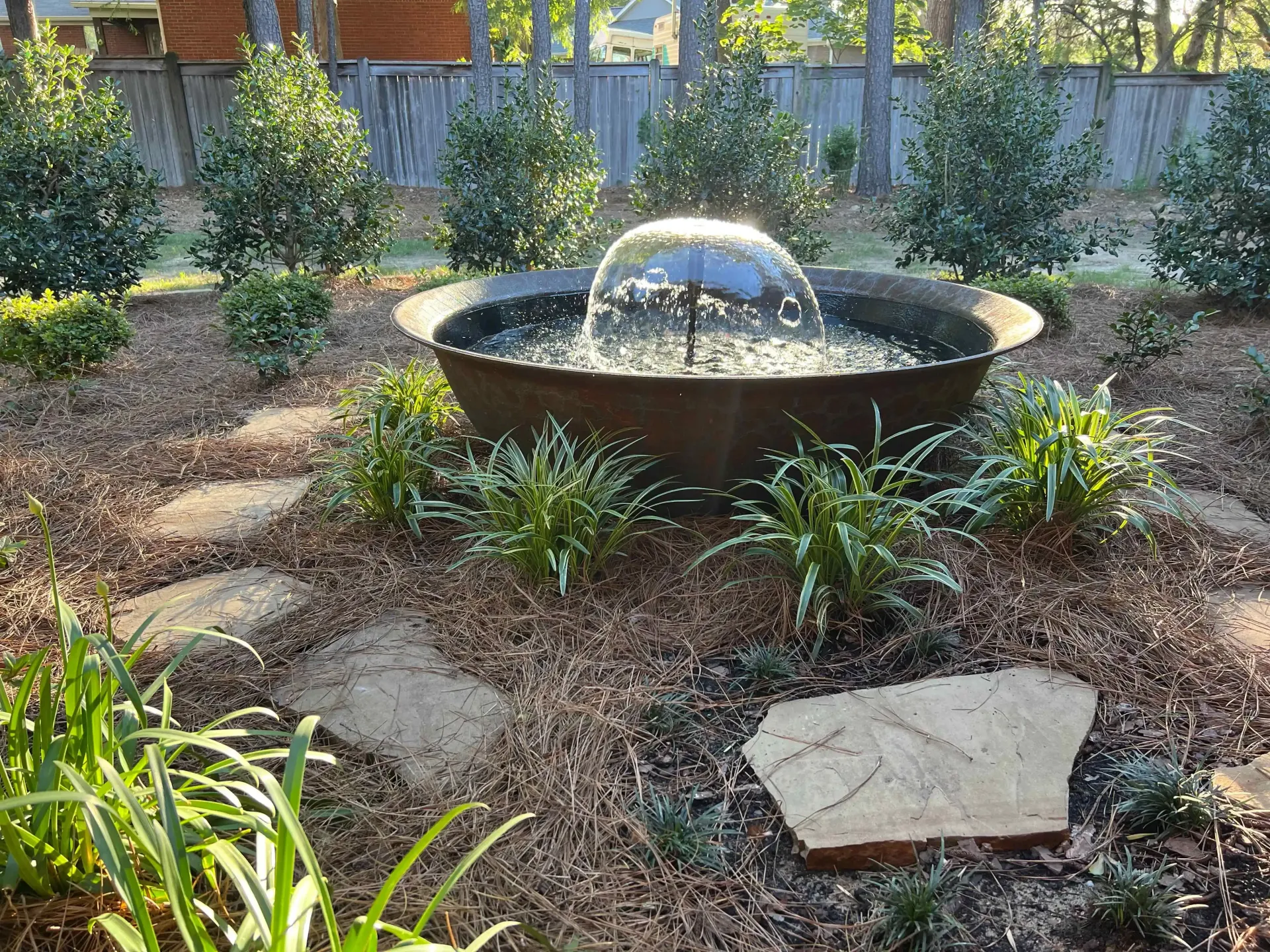 Fountain in a garden with stone path and greenery.