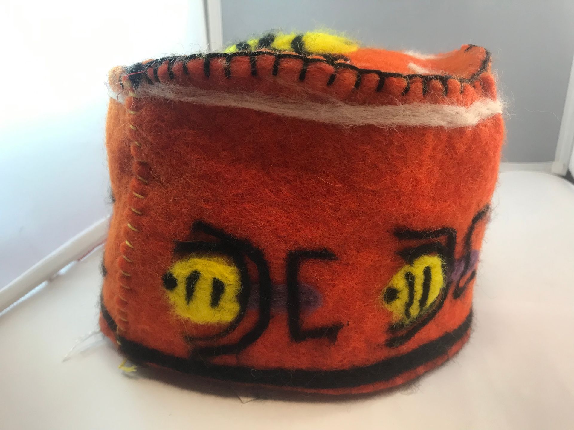 An orange hat with a yellow bee on it