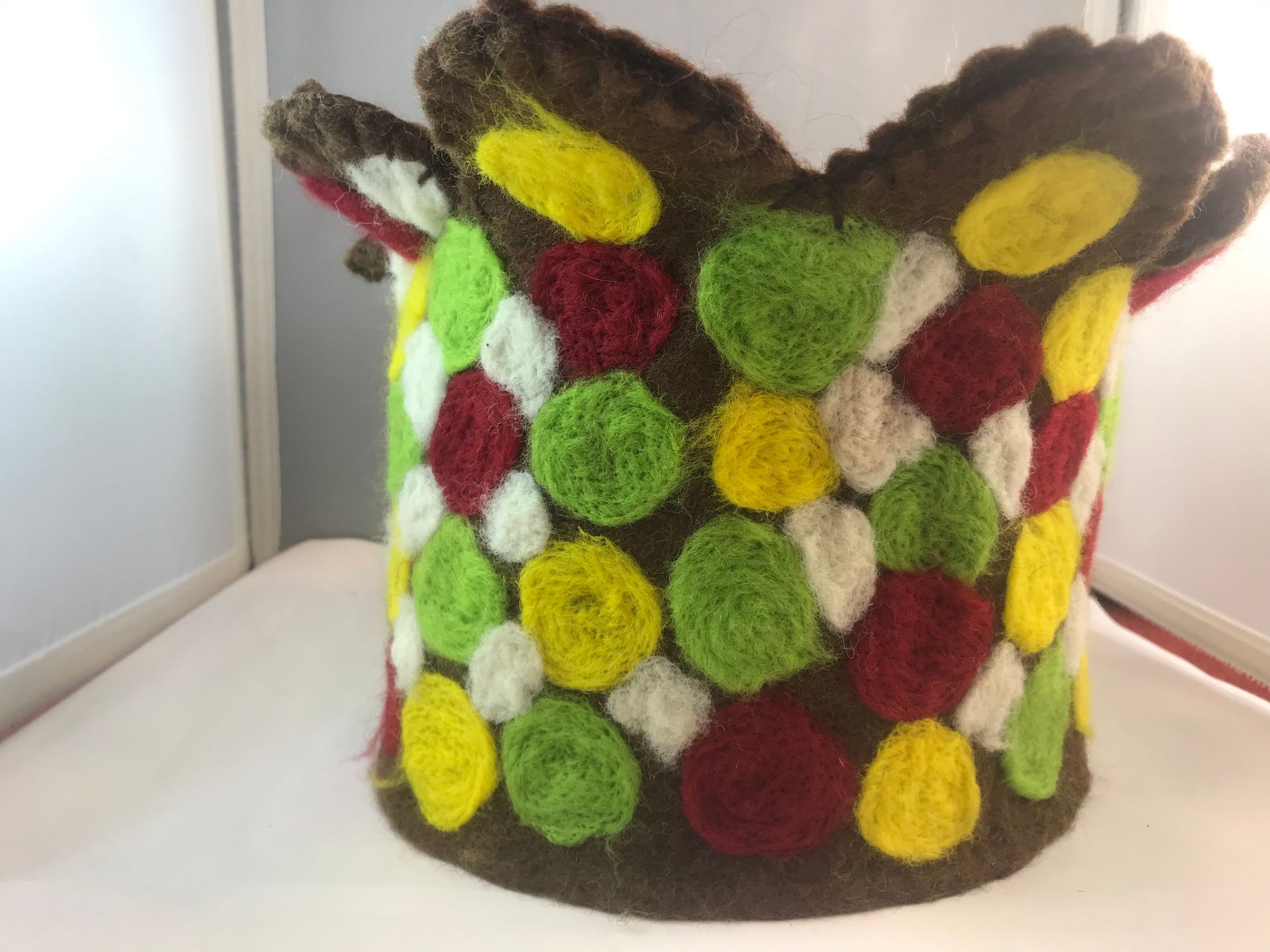 A colorful knitted item is sitting on a white table