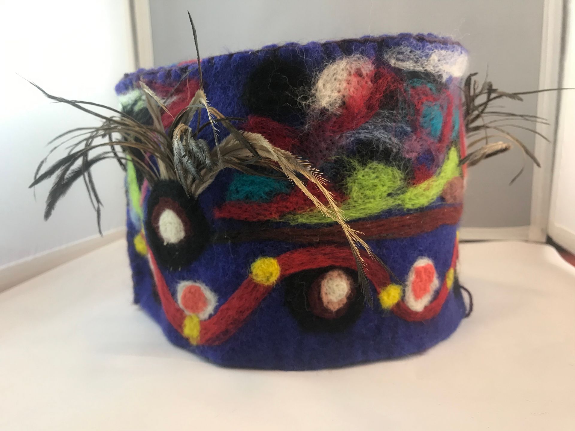 A purple hat with feathers on it is sitting on a white table.