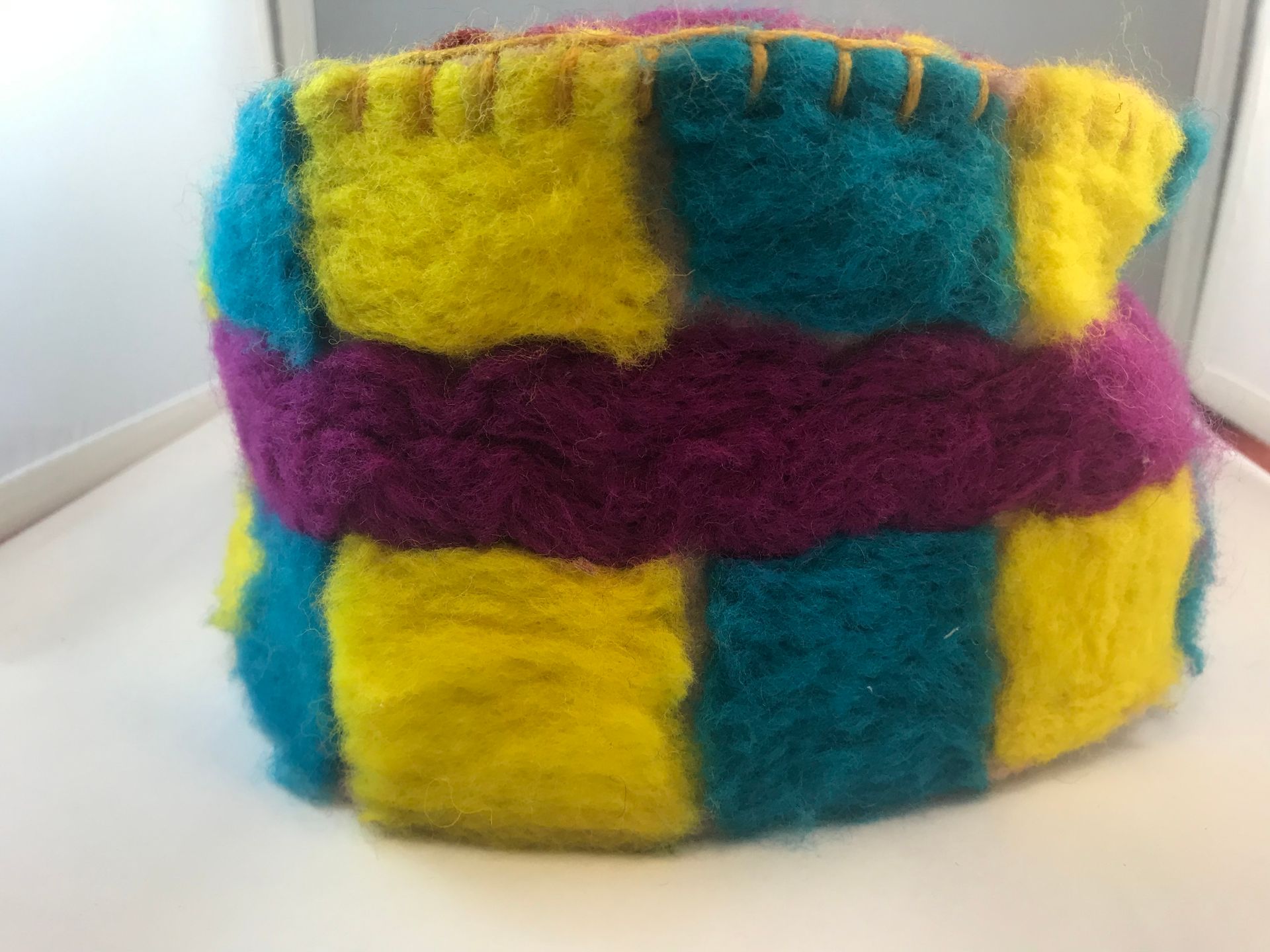A colorful knitted hat is sitting on a white table.