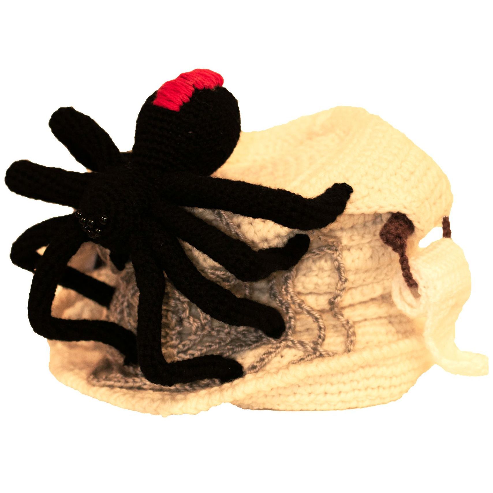 A stuffed spider is sitting on top of a white blanket