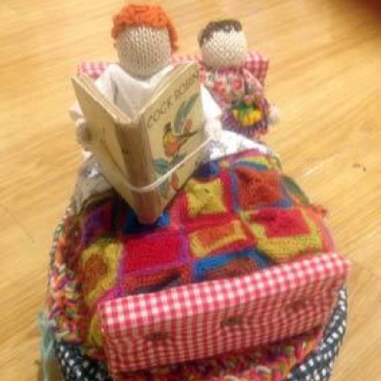 A crocheted doll is reading a book called cook book