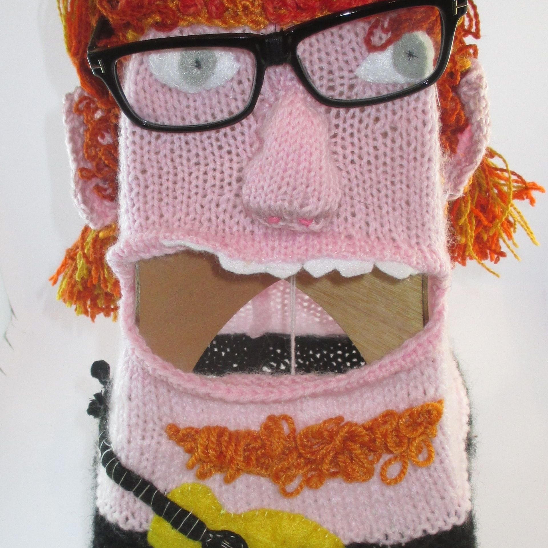 A knitted puppet with glasses and a yellow guitar