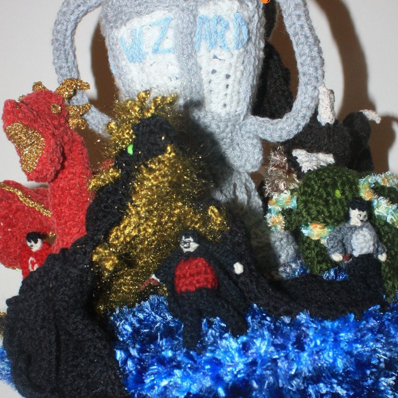 A group of stuffed animals are sitting around a crocheted trophy that says ' harry potter ' on it