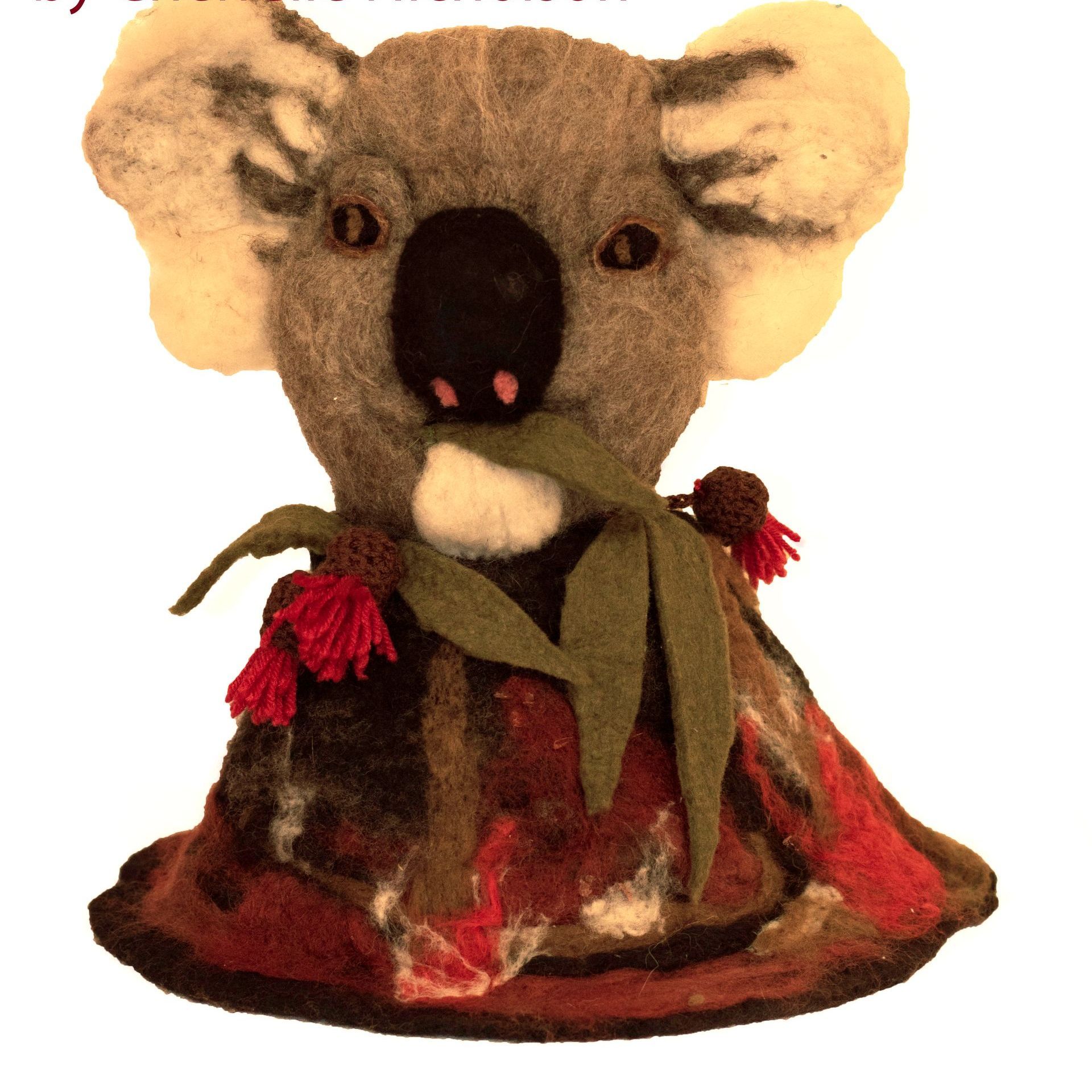A stuffed koala bear with a leaf in its mouth