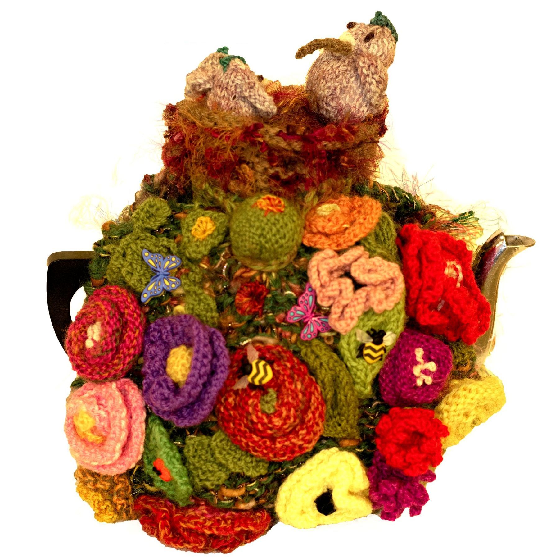 A teapot decorated with crocheted flowers and leaves
