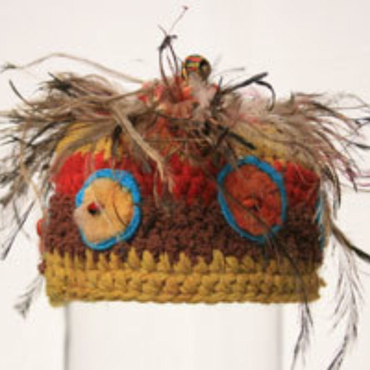 A crocheted hat with feathers and a bird on top