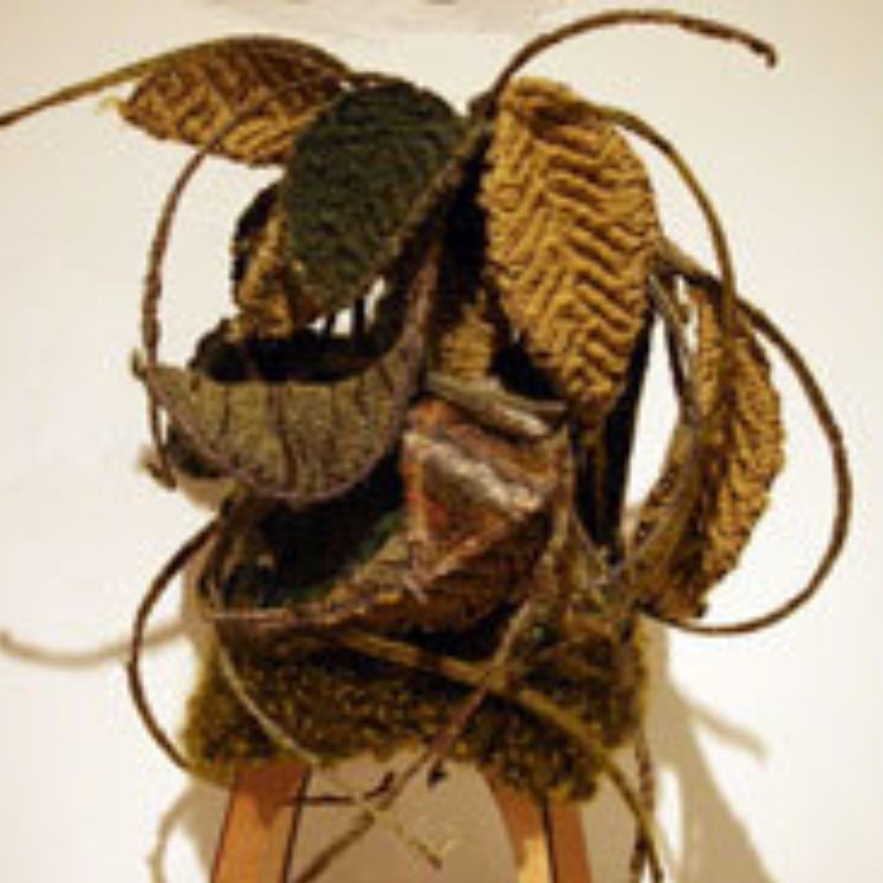 A sculpture made of leaves and branches is sitting on a stool.