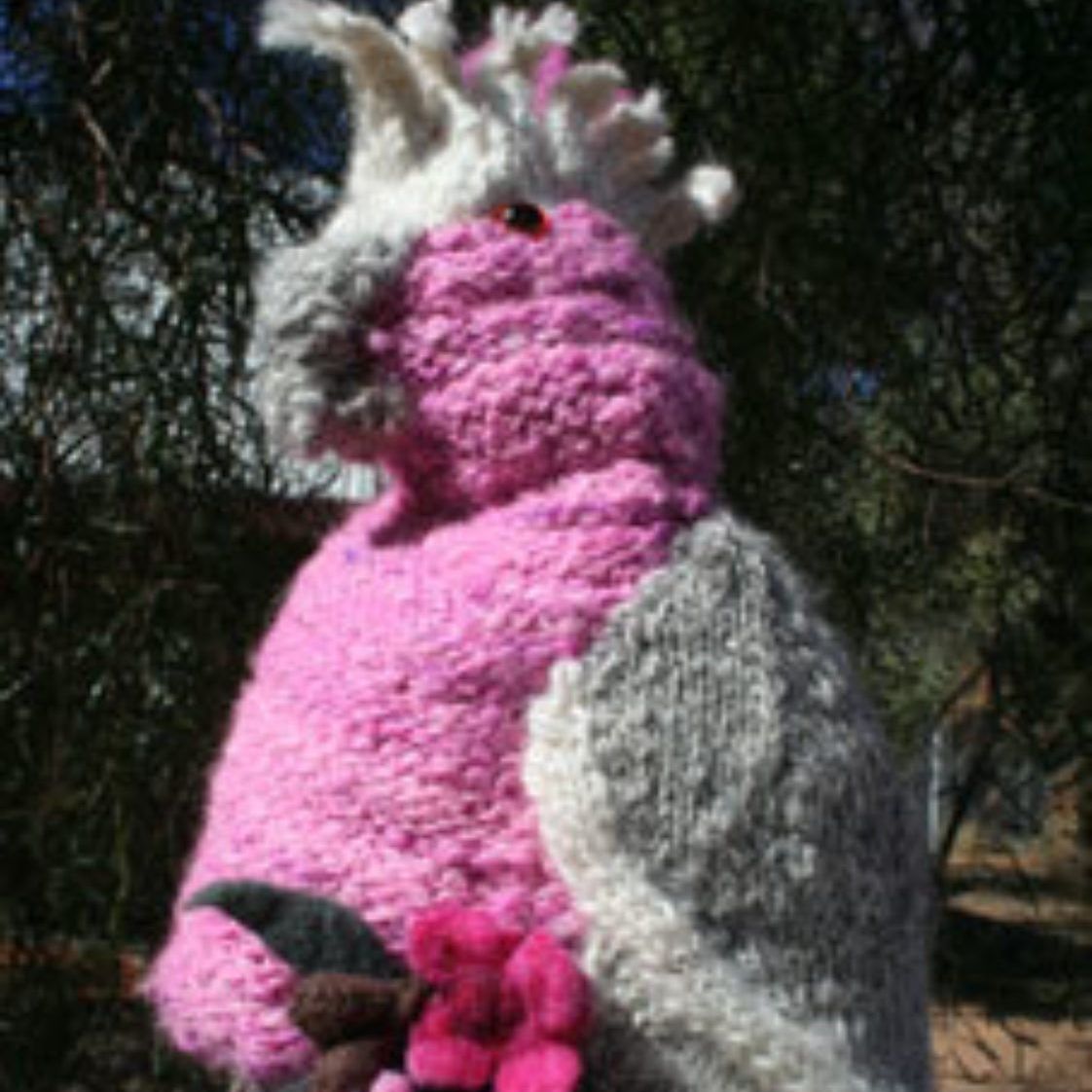 A pink and gray stuffed animal with a flower in its hand