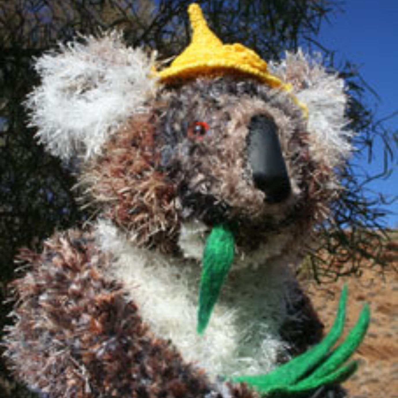 A stuffed koala bear wearing a yellow hat
