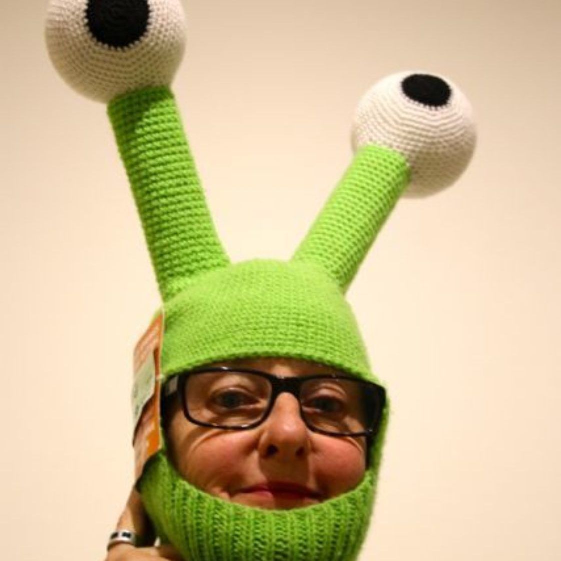 A woman wearing glasses and a green hat with big eyes