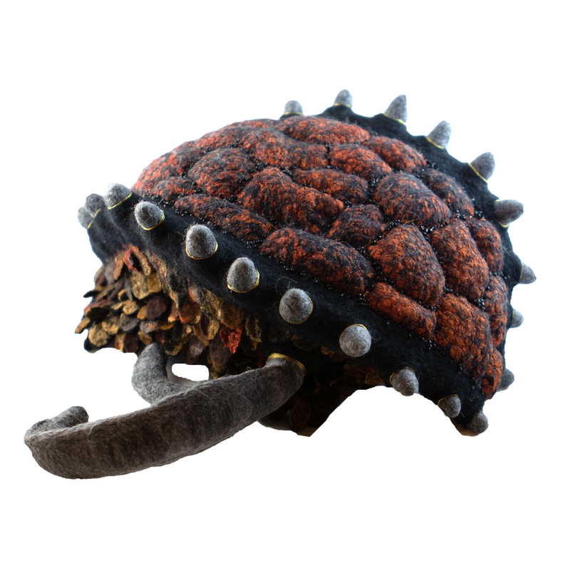 A stuffed animal with spikes on it is sitting on a white surface.