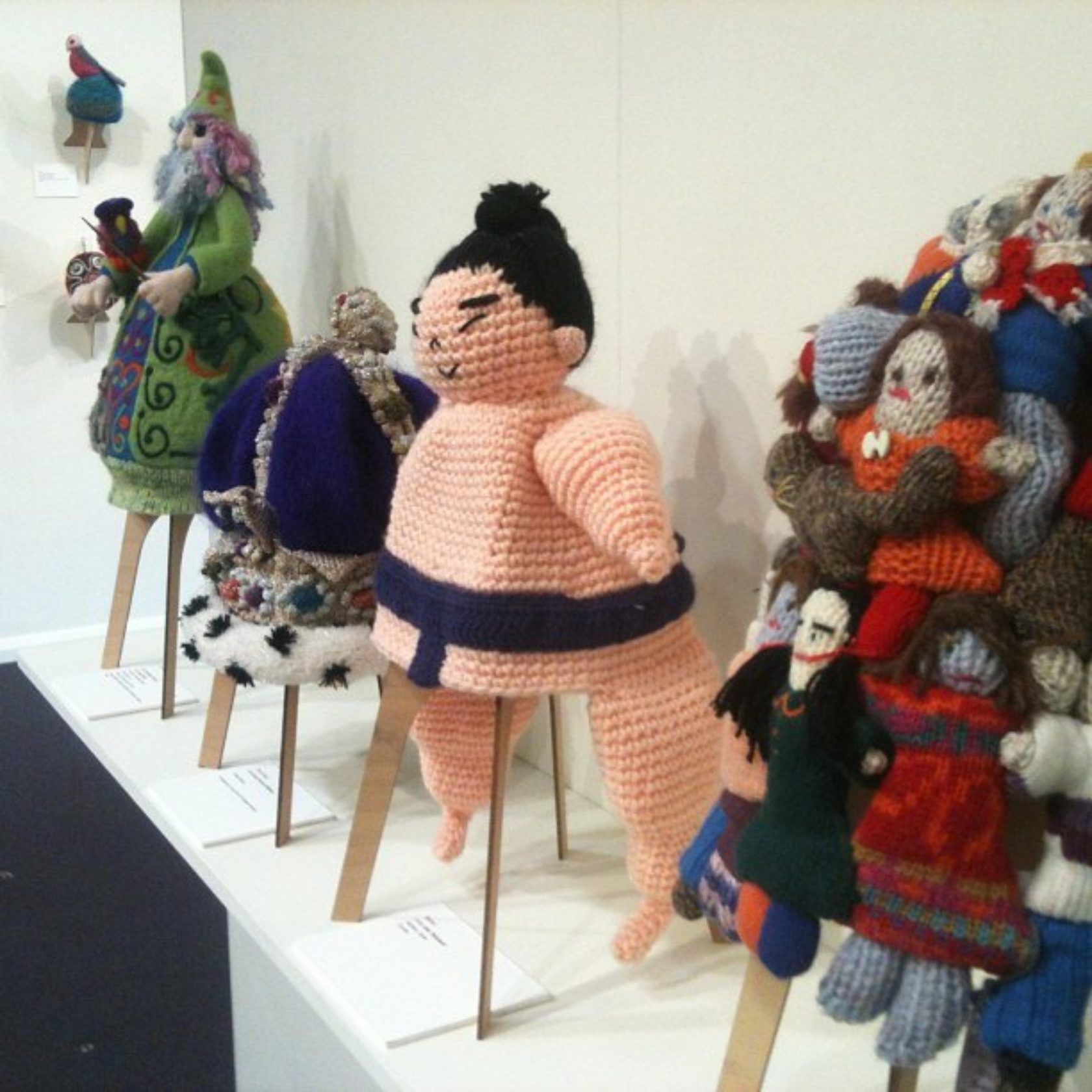 A row of knitted dolls including a sumo wrestler