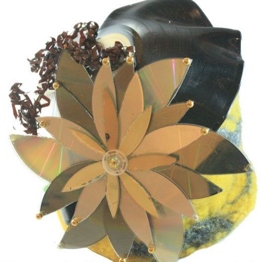A flower made out of cds is on a yellow object