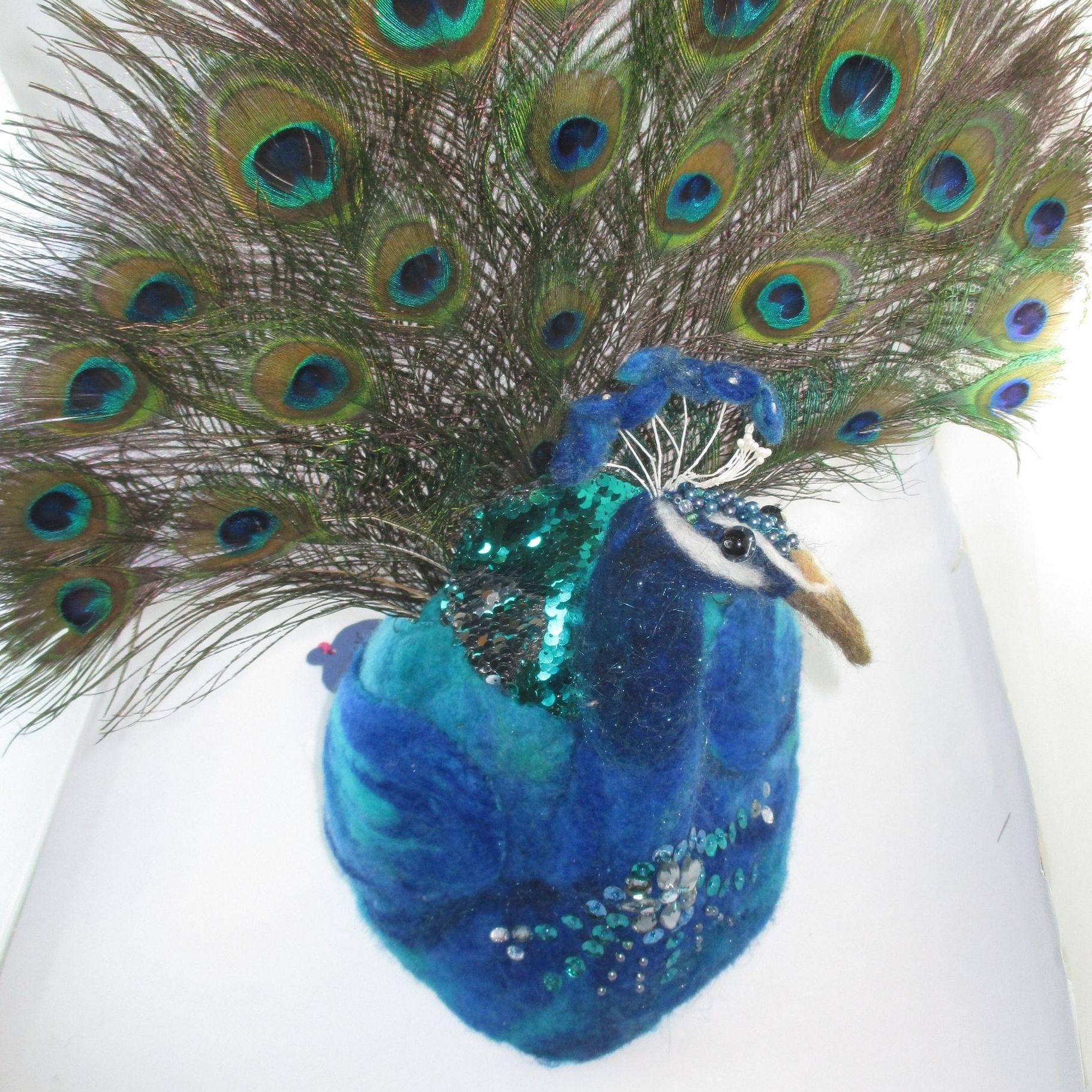 A stuffed peacock with feathers spread out on a white surface