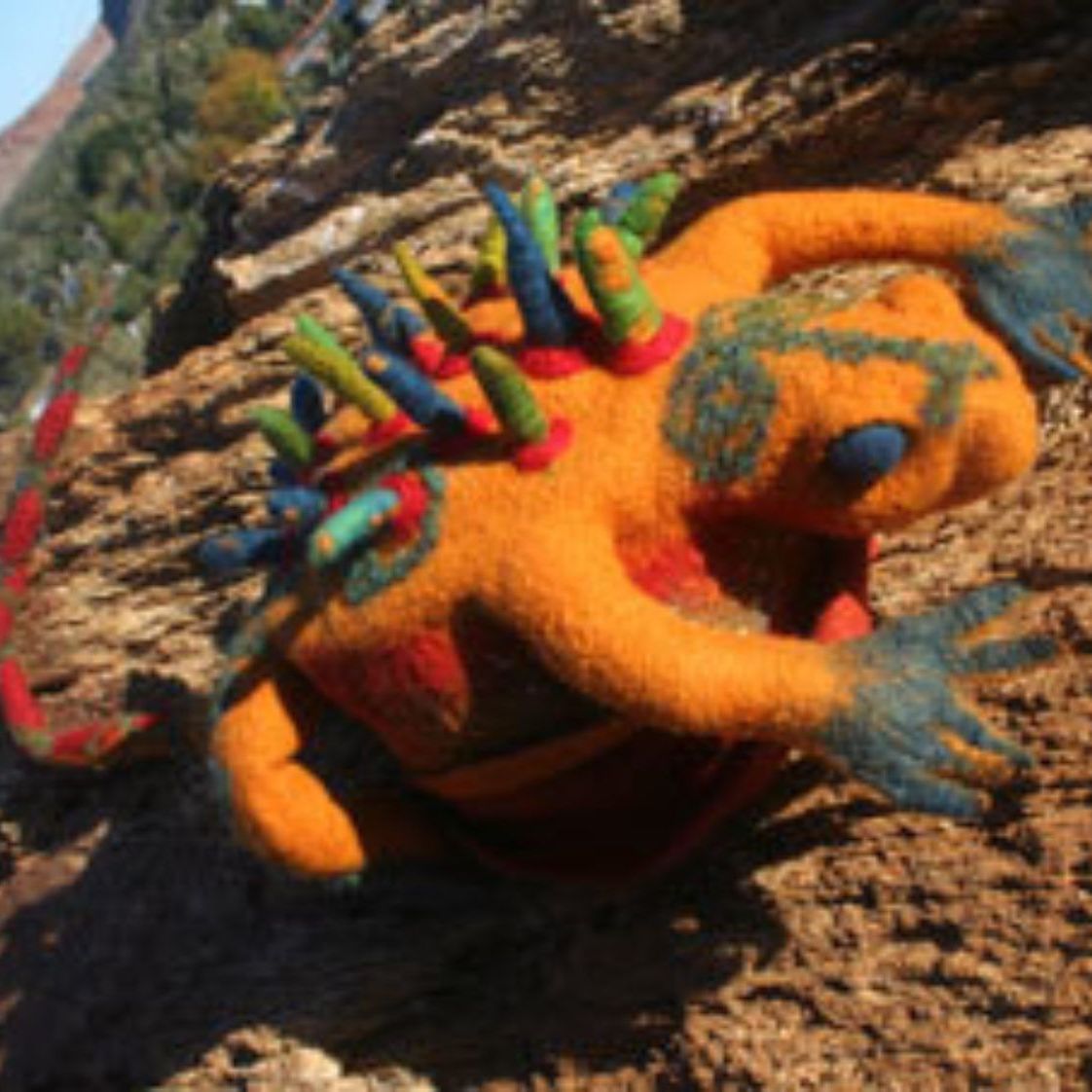 A stuffed animal is laying on its back on a rock