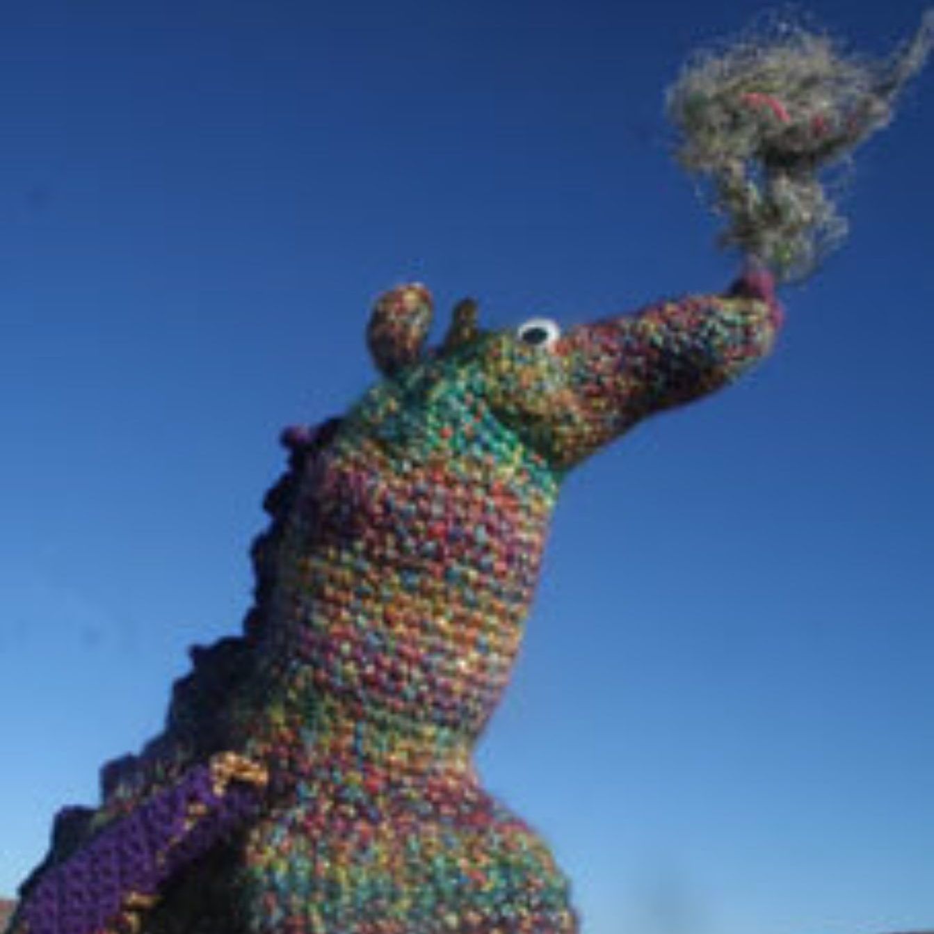 A colorful stuffed animal with a blue sky in the background.