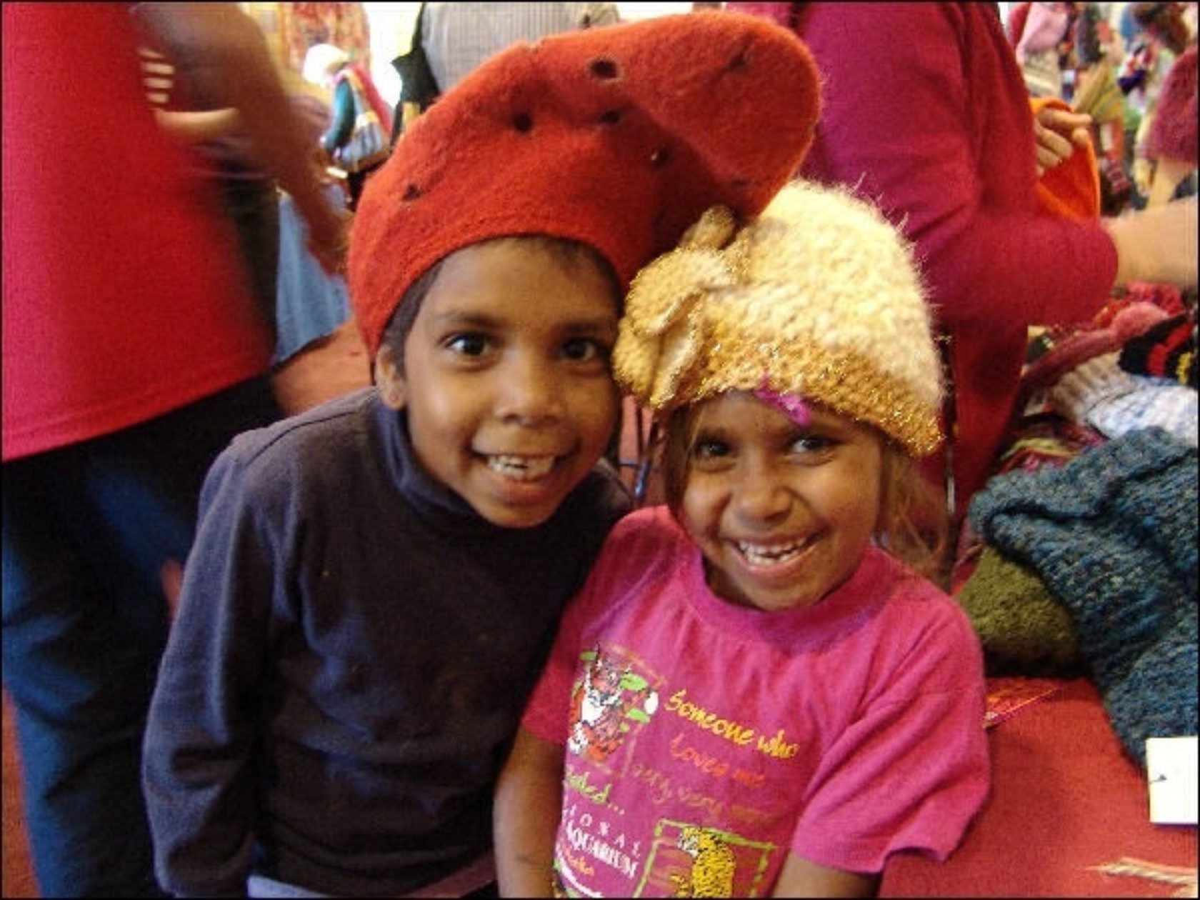 A boy and a girl wearing hats are posing for a picture