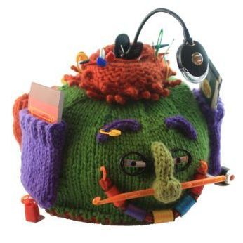 A green and purple knitted object with a face on it