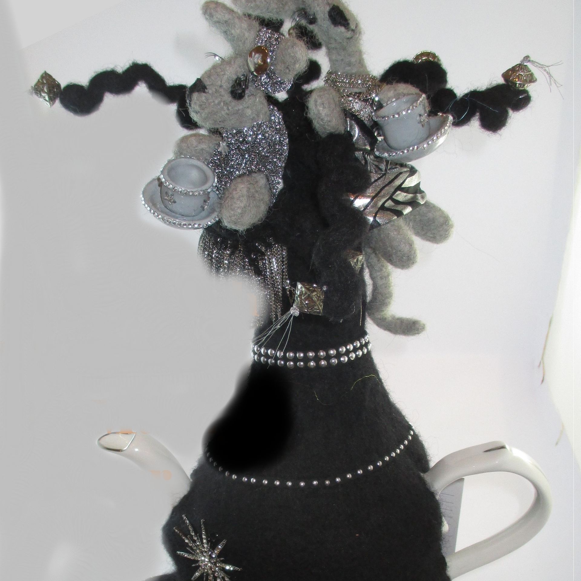 A black teapot with stuffed animals on top of it