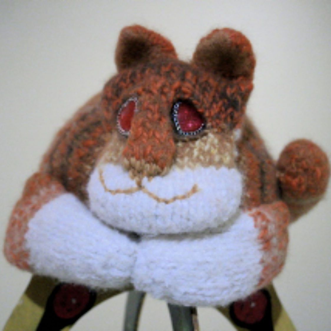 A stuffed animal with red eyes is sitting on a ladder