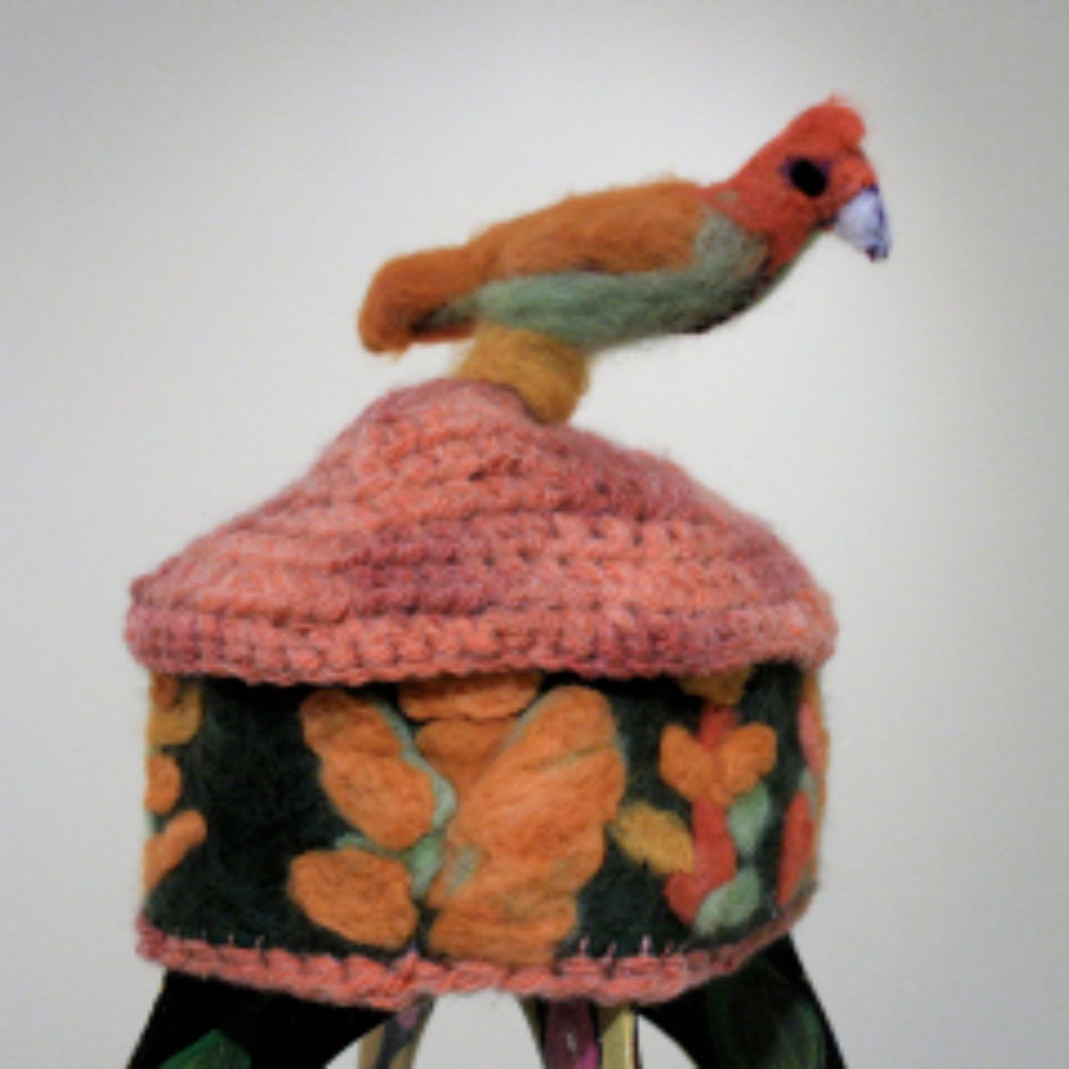 A stuffed bird is sitting on top of a crocheted box