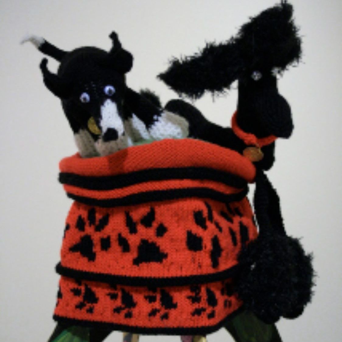 A black and white stuffed animal is sitting in an orange and black bag