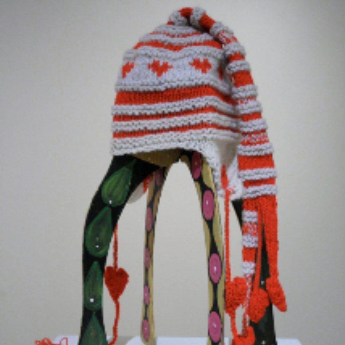 A knitted hat with hearts on it sits on a table