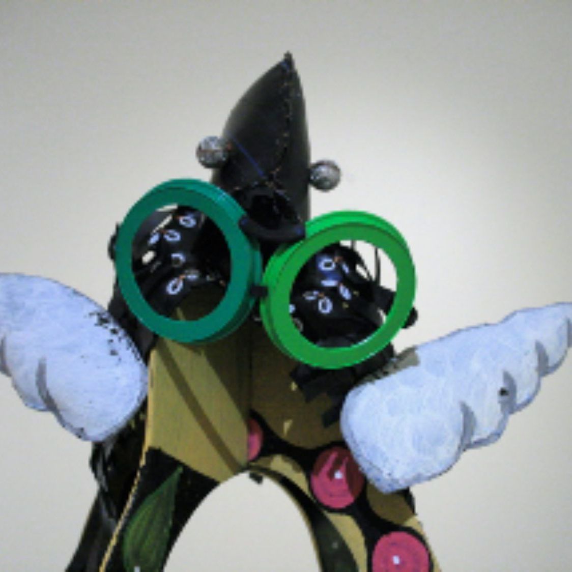A statue of a clown with green glasses and white wings