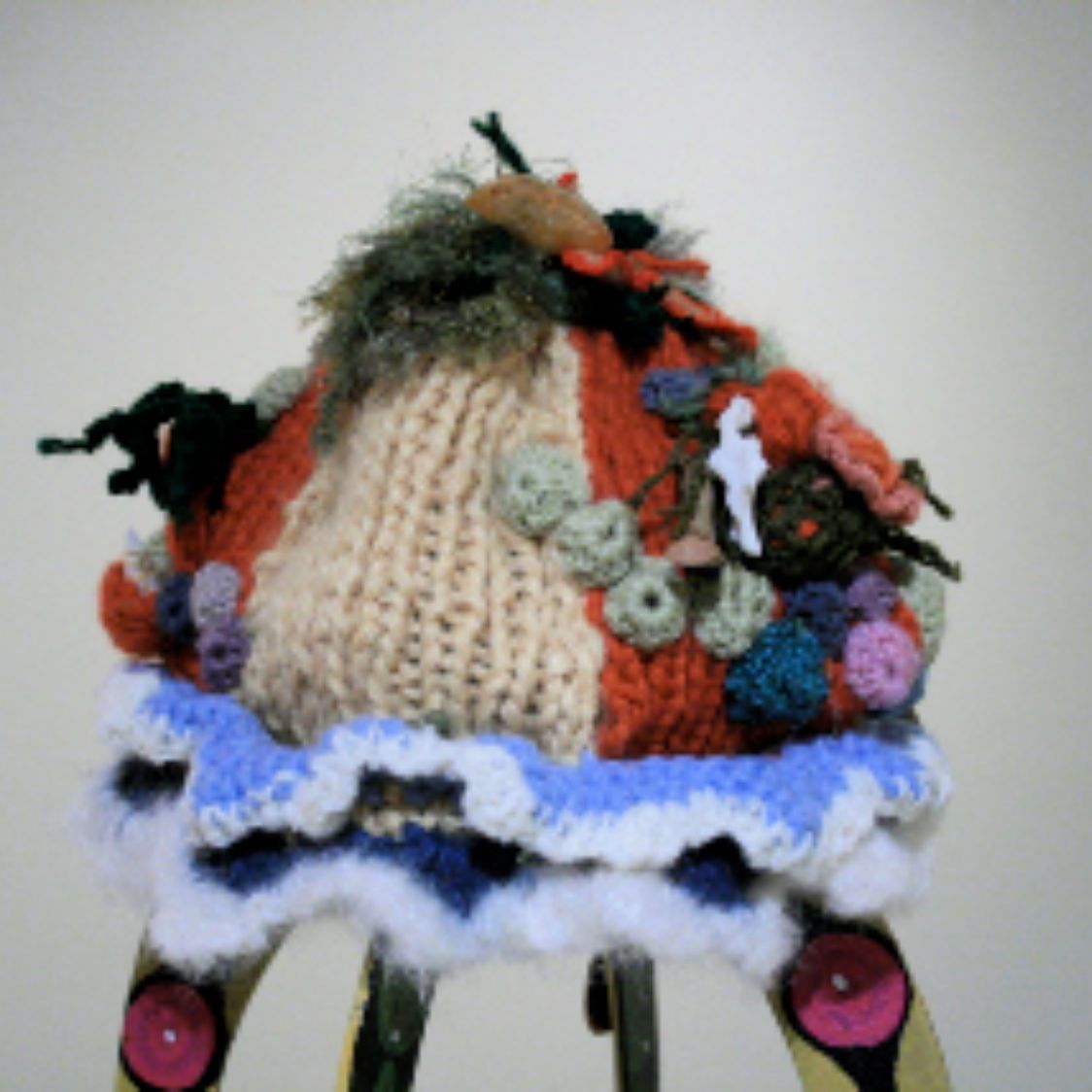 A crocheted hat is sitting on top of a ladder