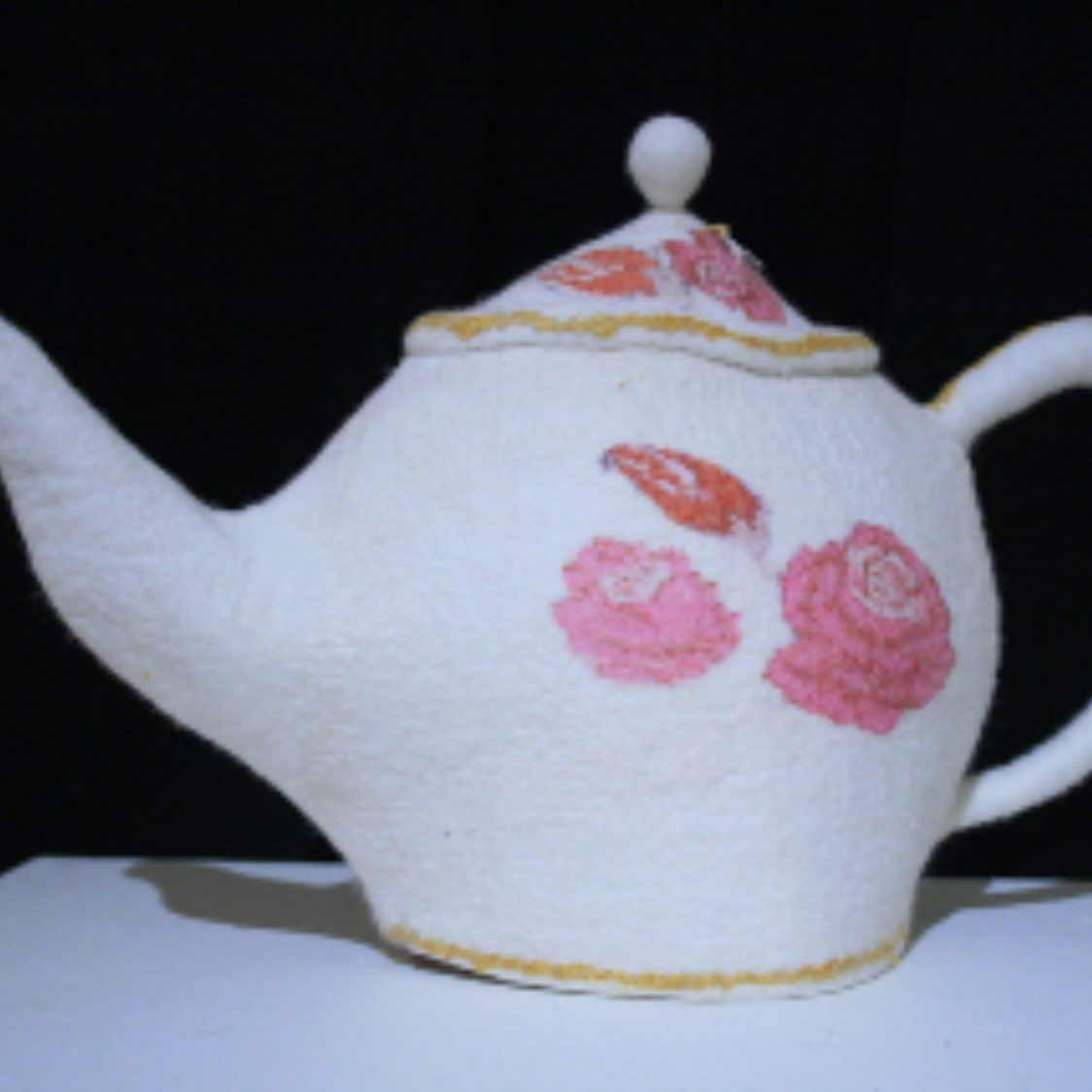 A white teapot with pink roses painted on it