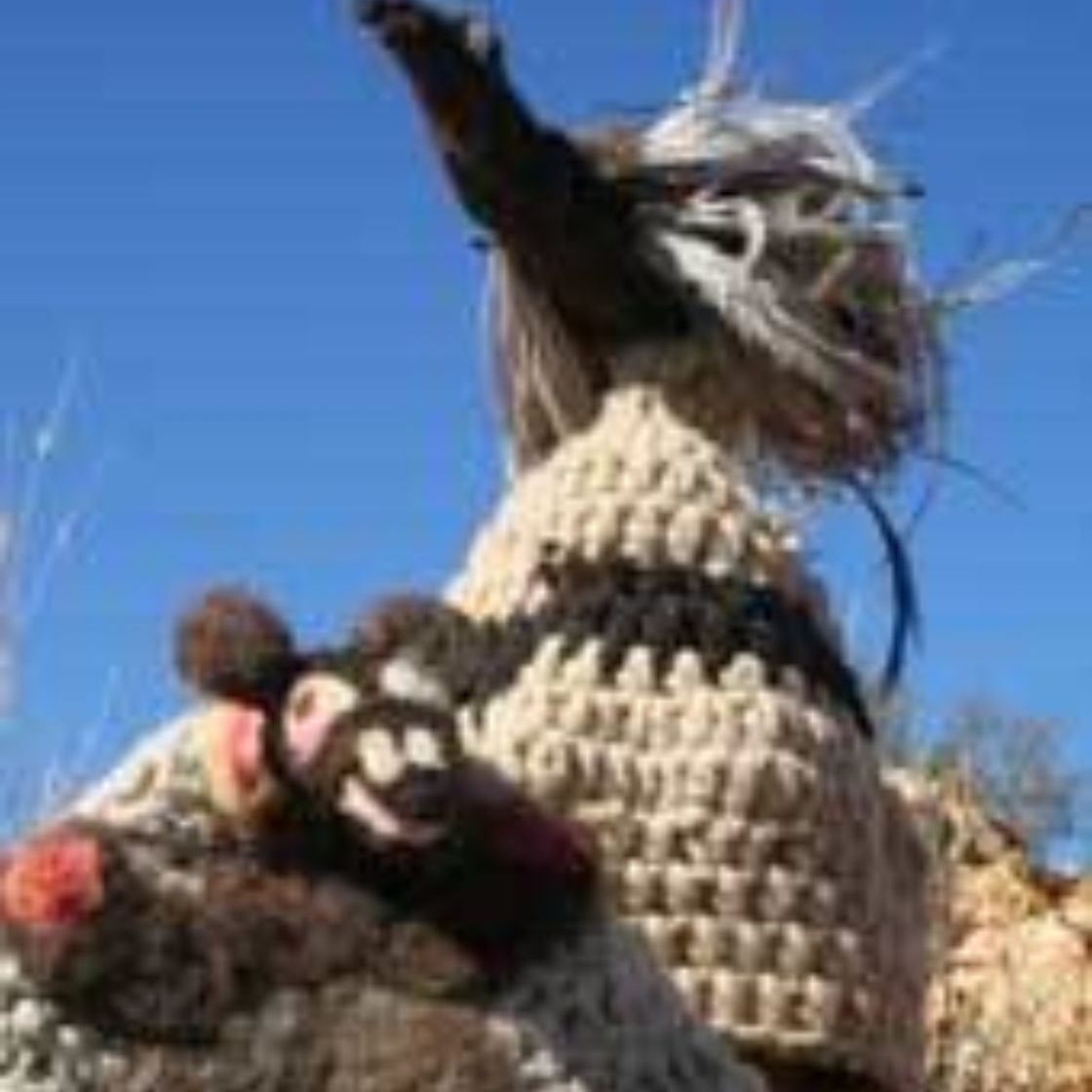 A close up of a llama wearing a knitted sweater.