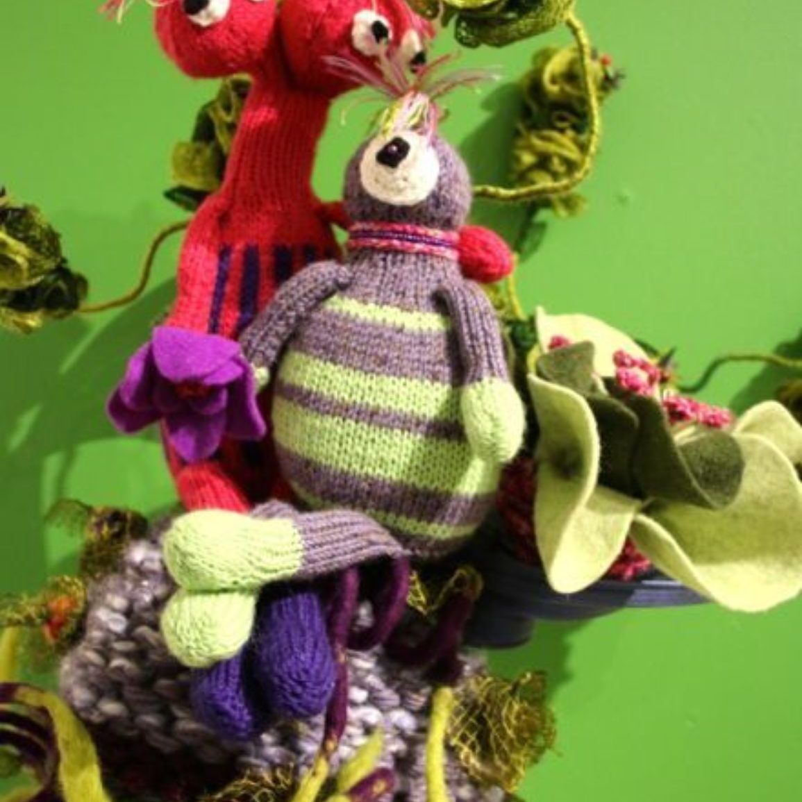 Two stuffed animals are sitting next to each other on a green background