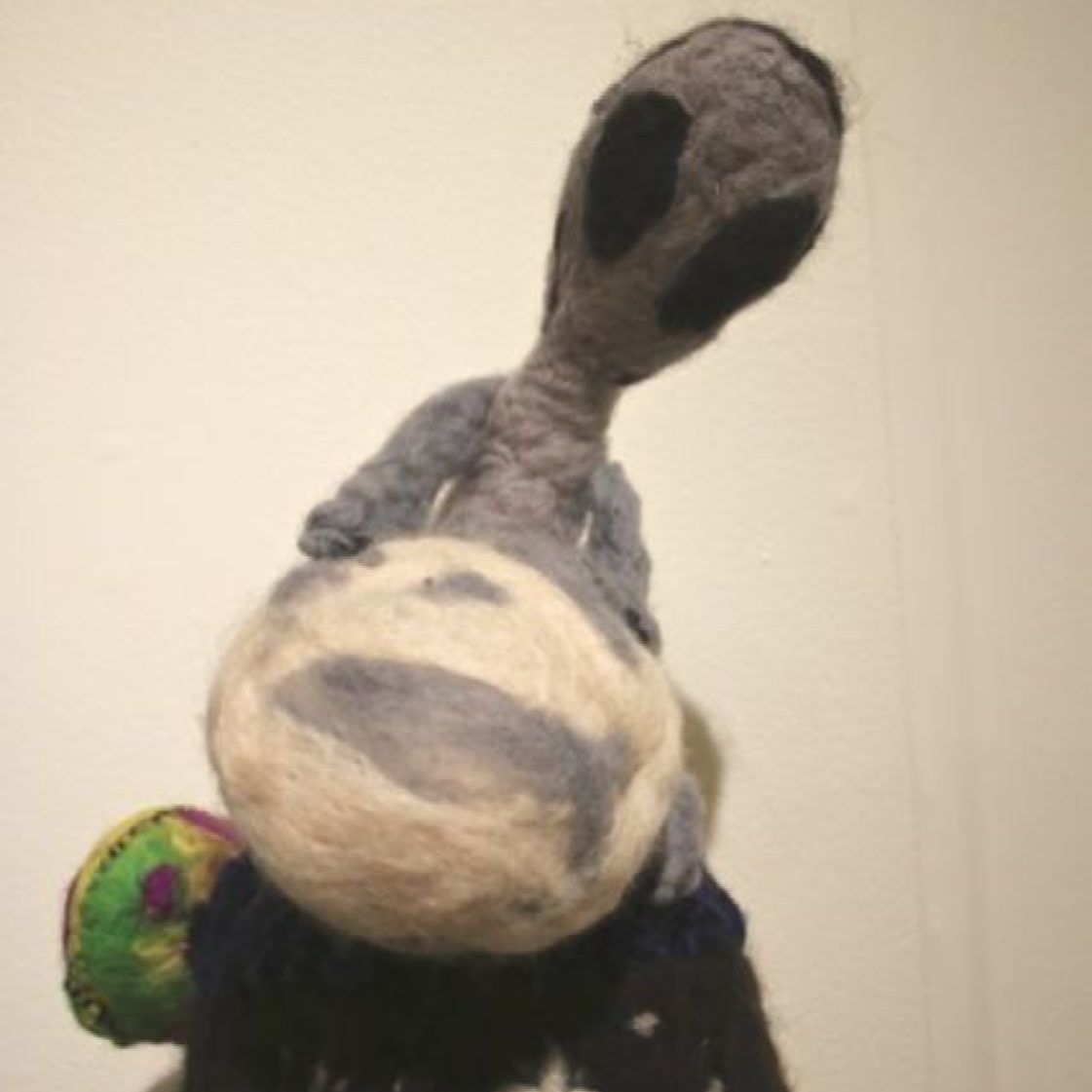 A stuffed alien is holding a ball on its back