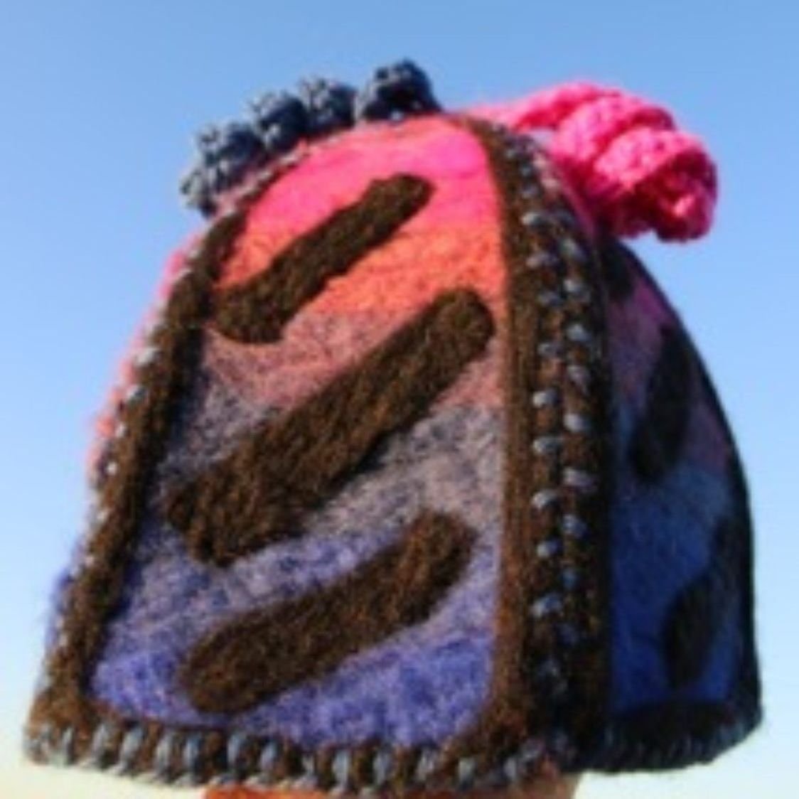 A person wearing a colorful hat with a pink ponytail