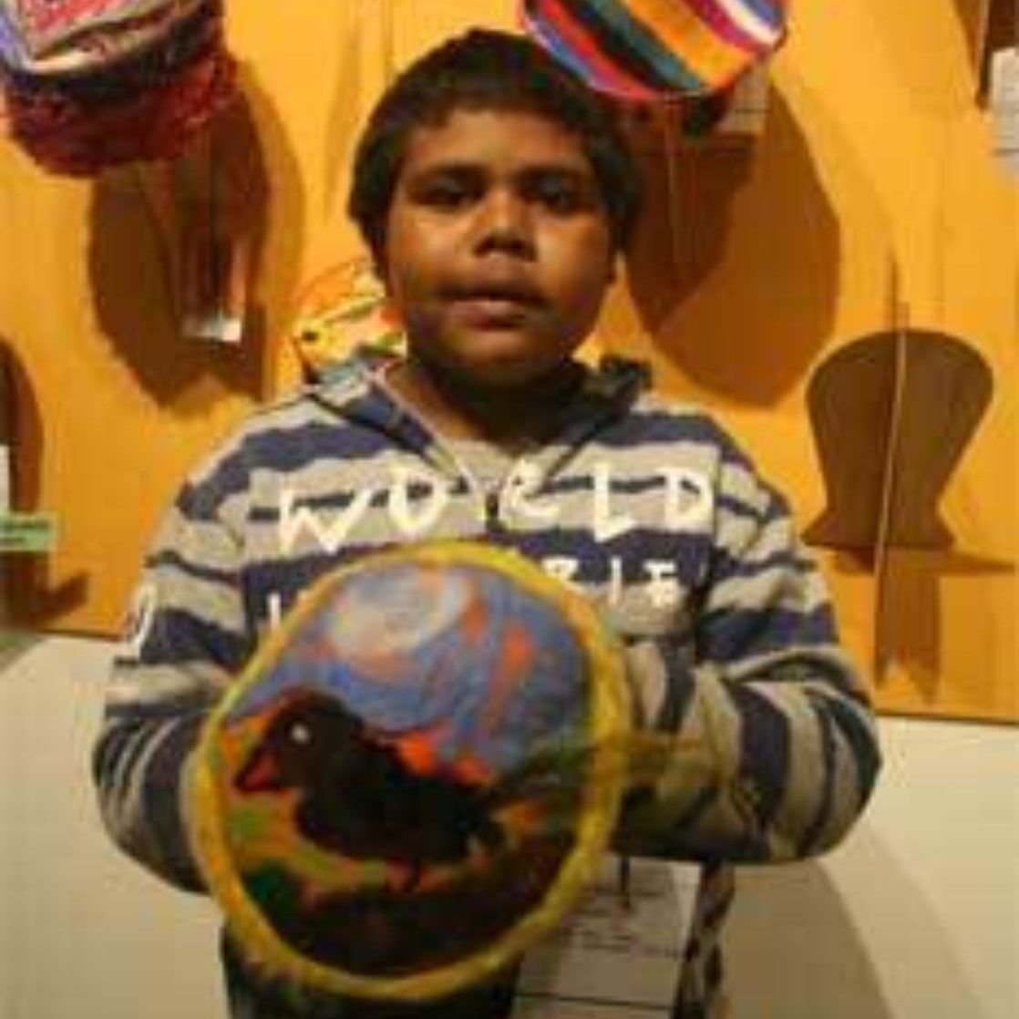 A young boy wearing a world sweatshirt is holding a painting of a horse.