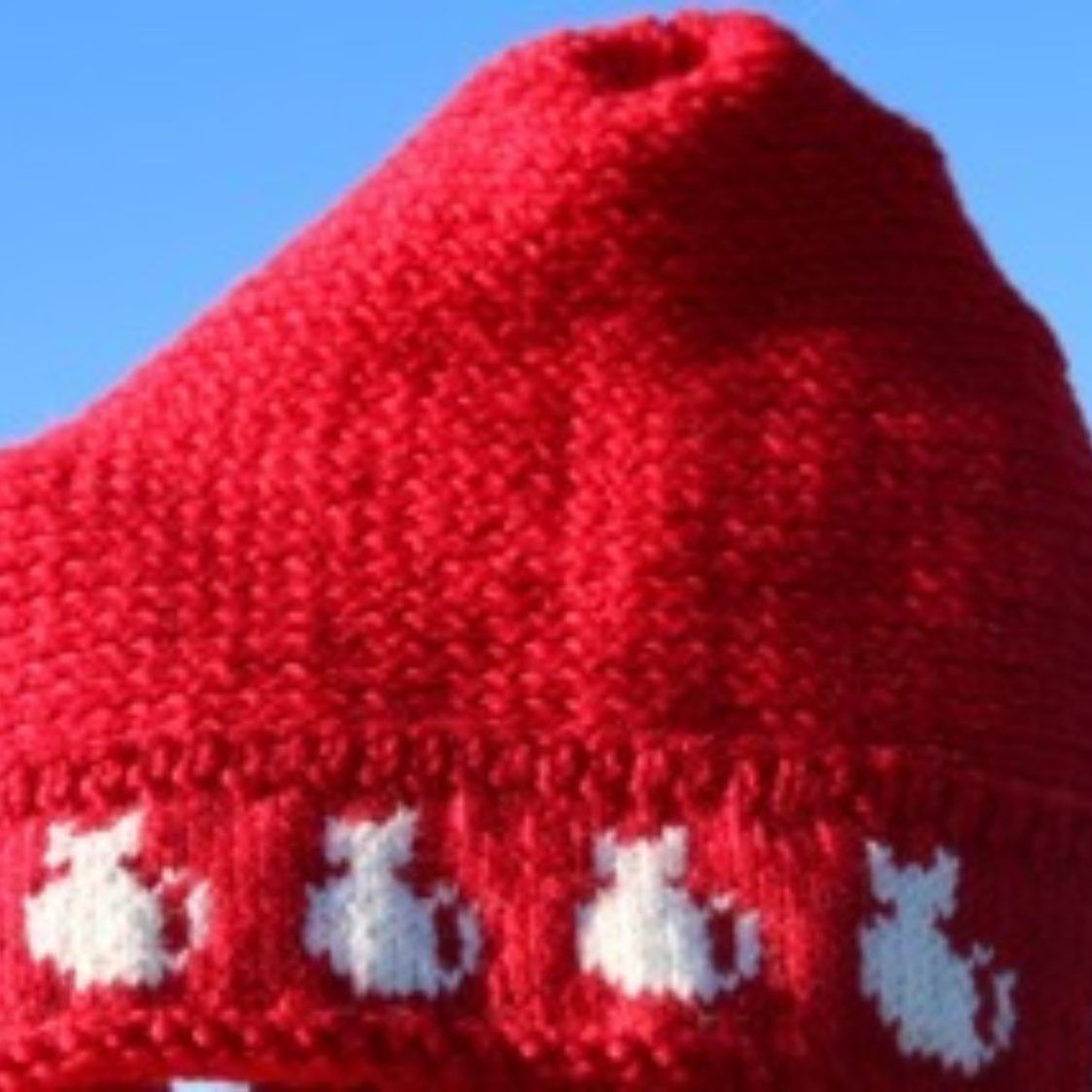 A red knitted hat with white cats on it